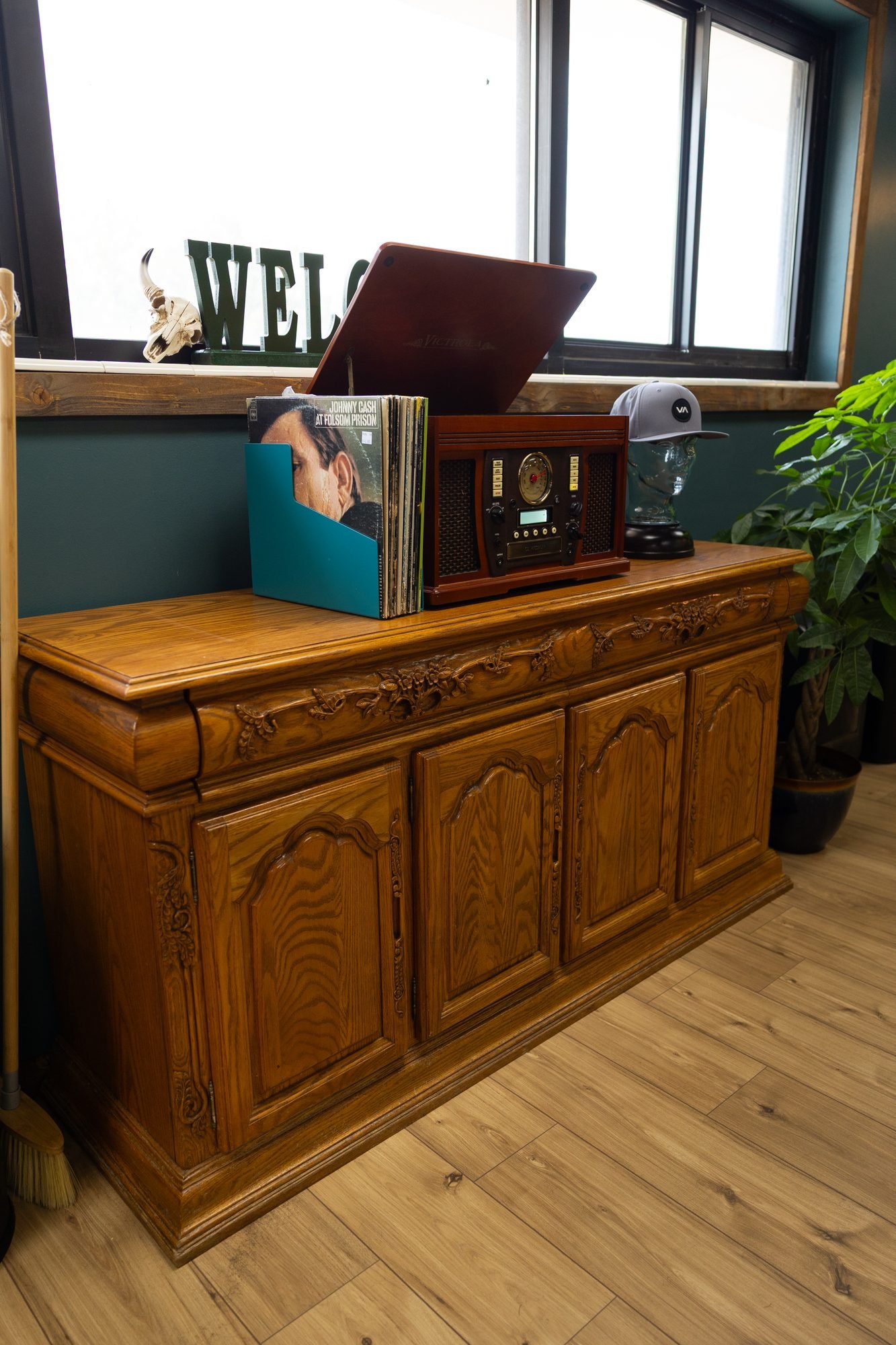 A carved wooden cabinet with a record player and records in a teal barbershop