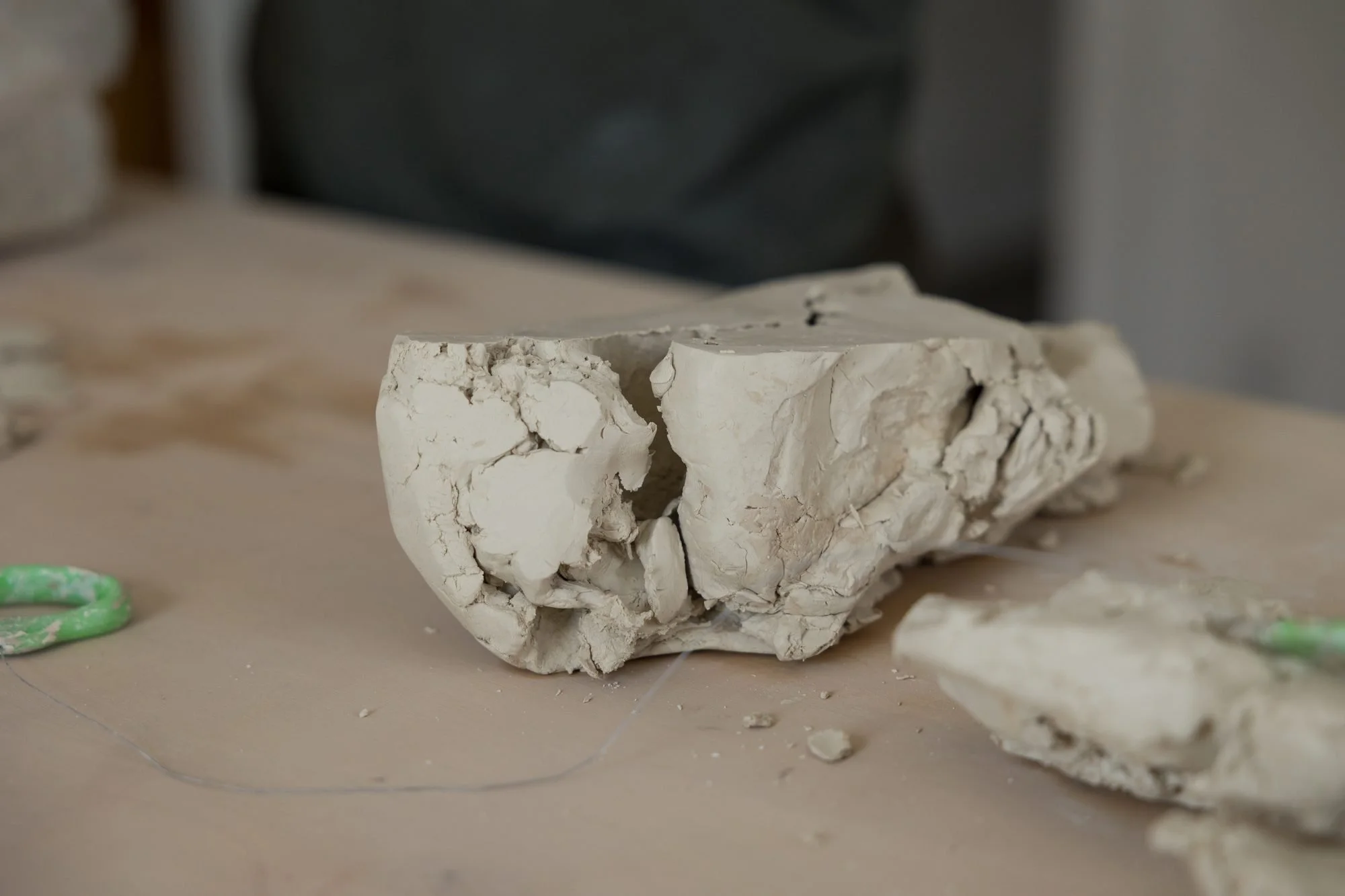 A lump of pale raw clay resting on a work table in soft light