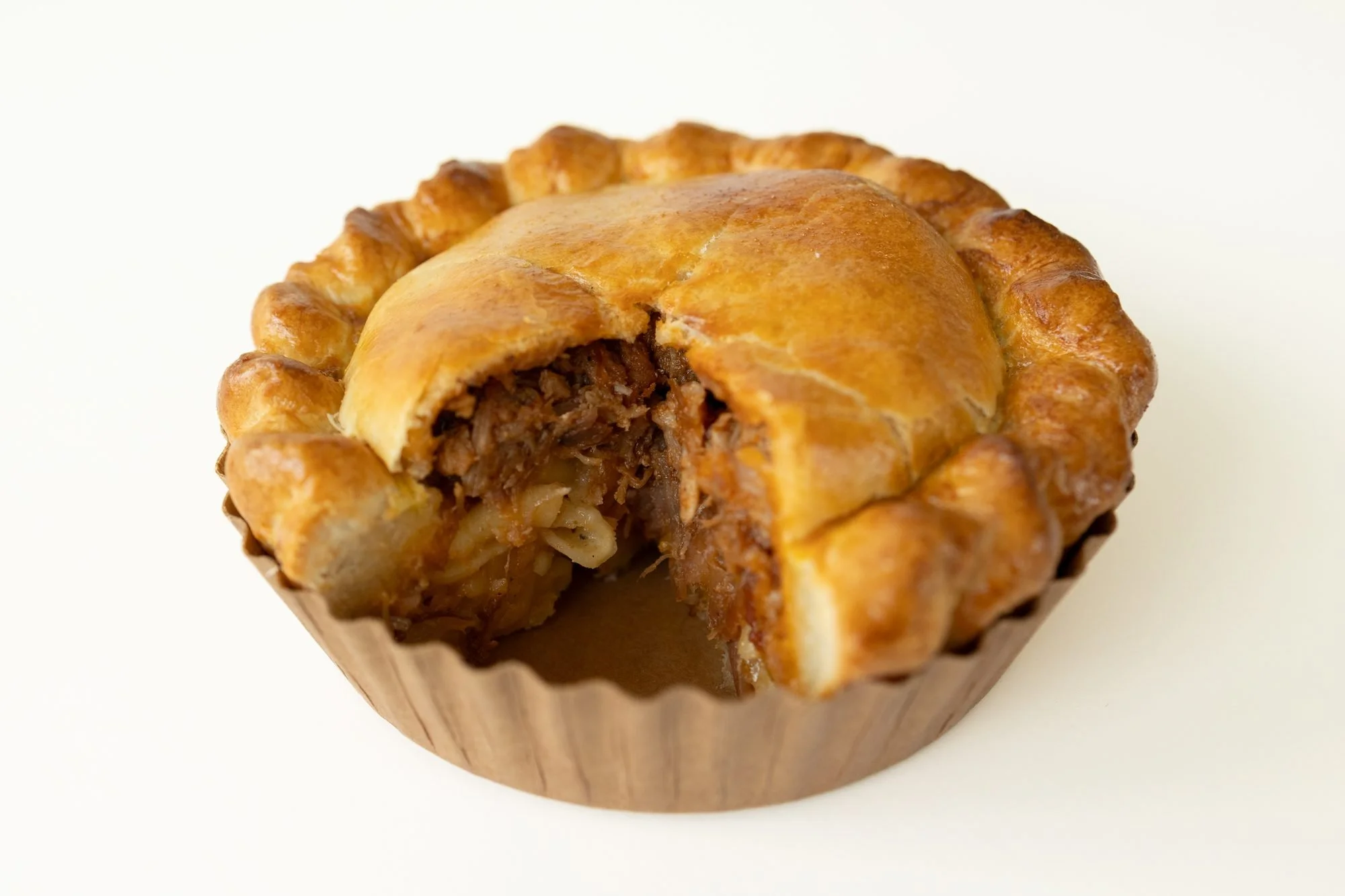 A golden Crust Club hand pie with a wedge cut out to show the filling, on a white background