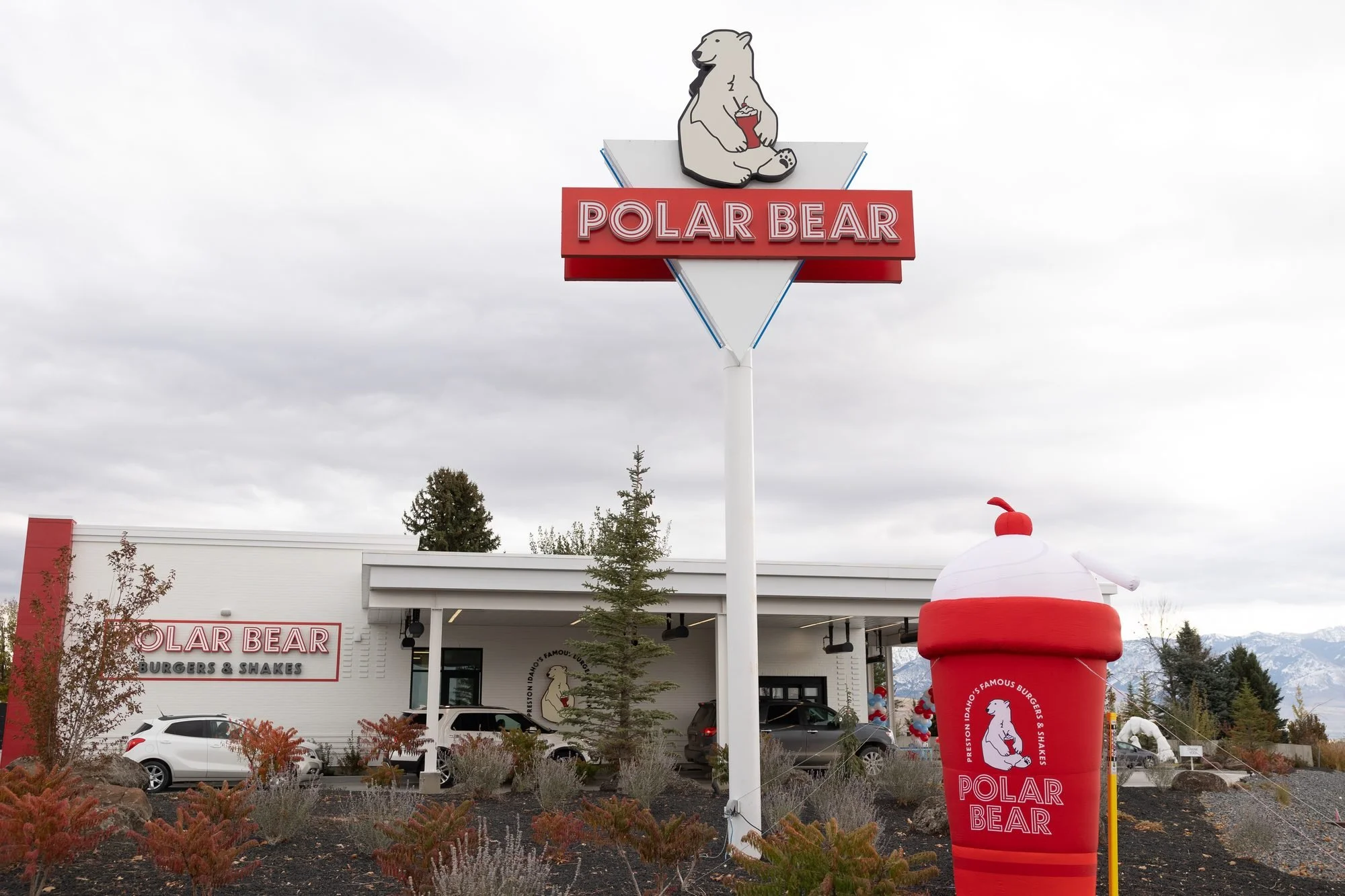 A Polar Bear drive-in with its tall sign and a giant inflatable shake out front under a cloudy sky