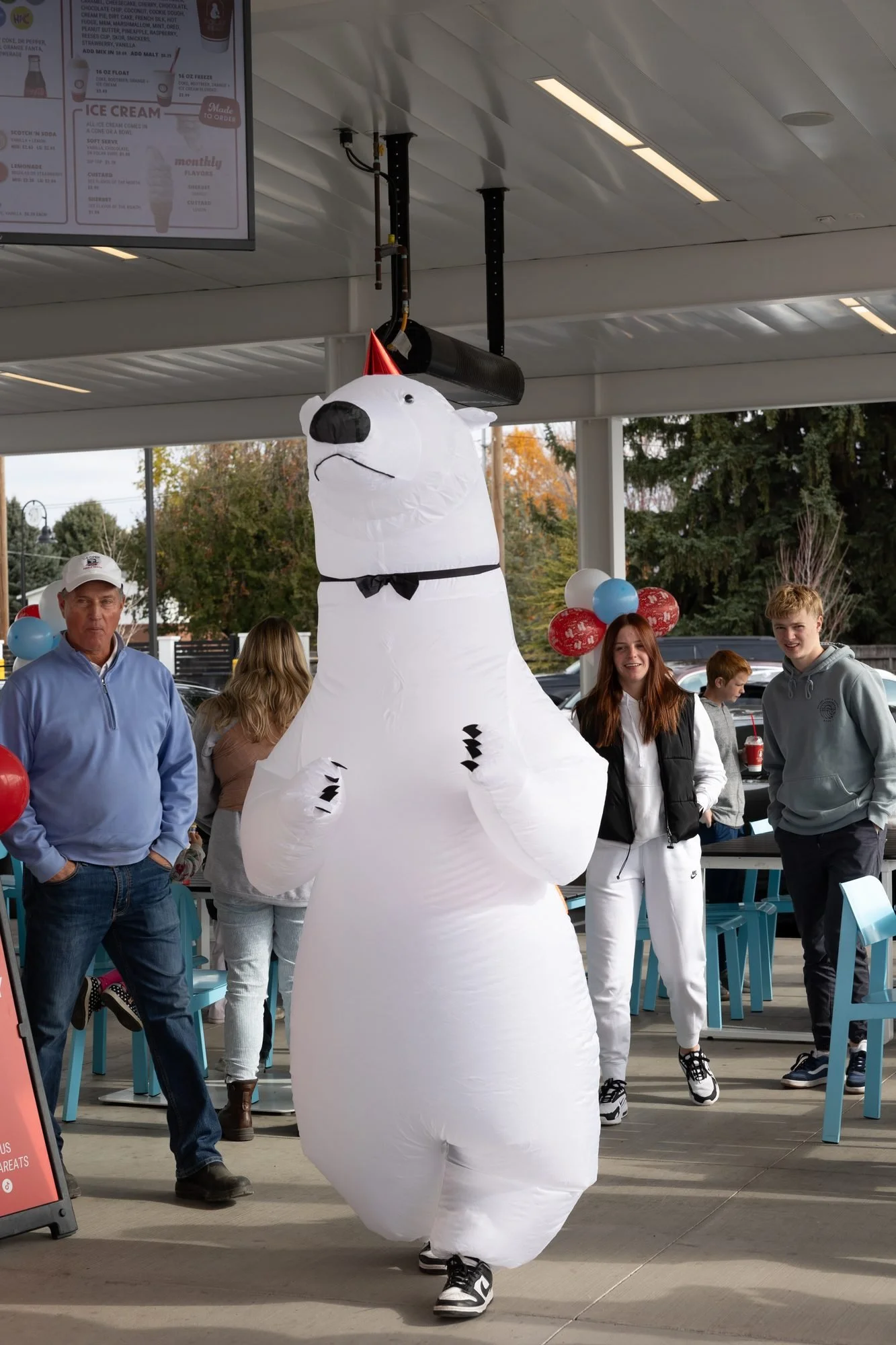 A person in an inflatable polar bear costume walks through a crowd outside the shop