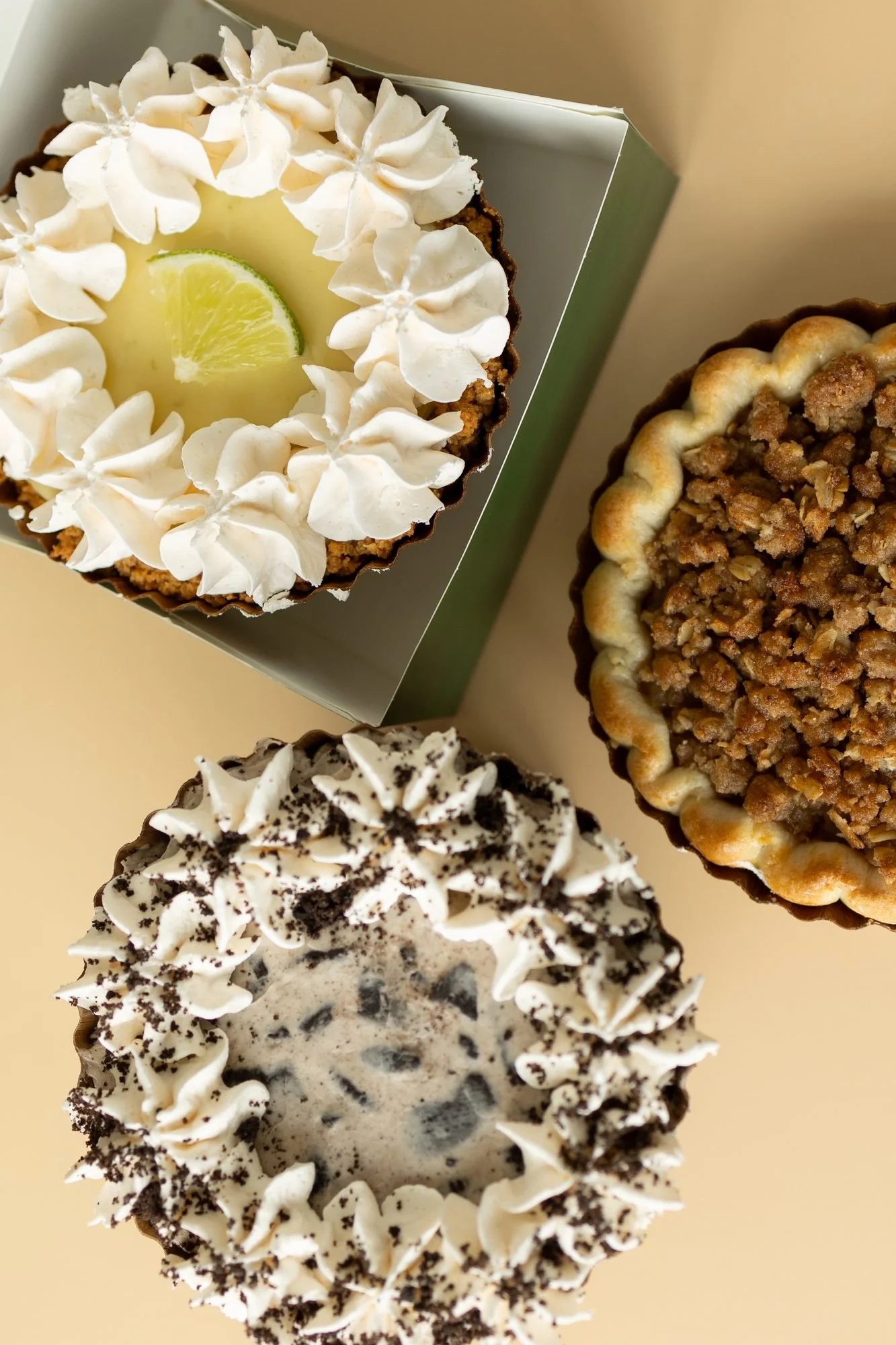 Crust Club key lime, crumble and cookie pies, one resting on a gray box, seen from above