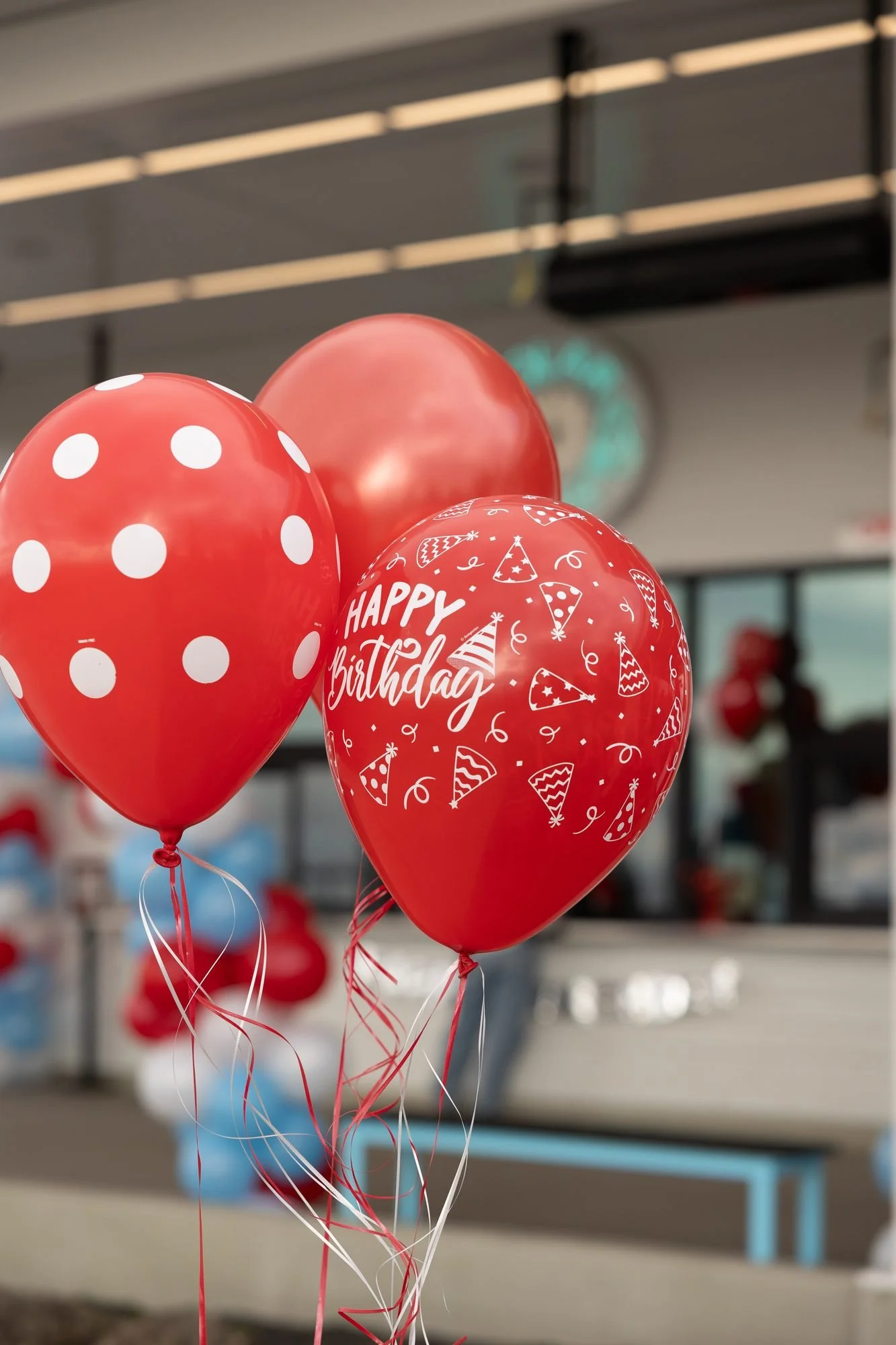 Red and white polka dot and Happy Birthday balloons outside a shop window