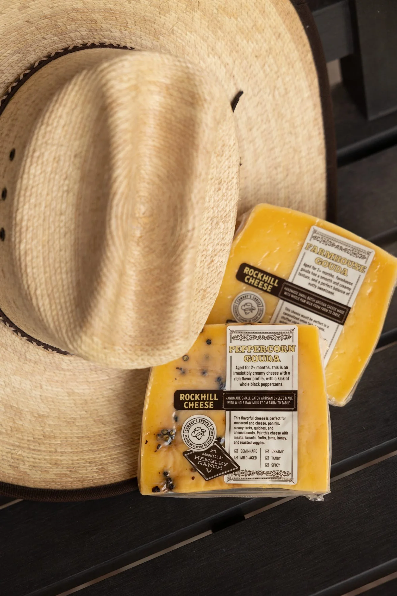 Two wedges of Rockhill Cheese resting against a straw cowboy hat on a dark surface