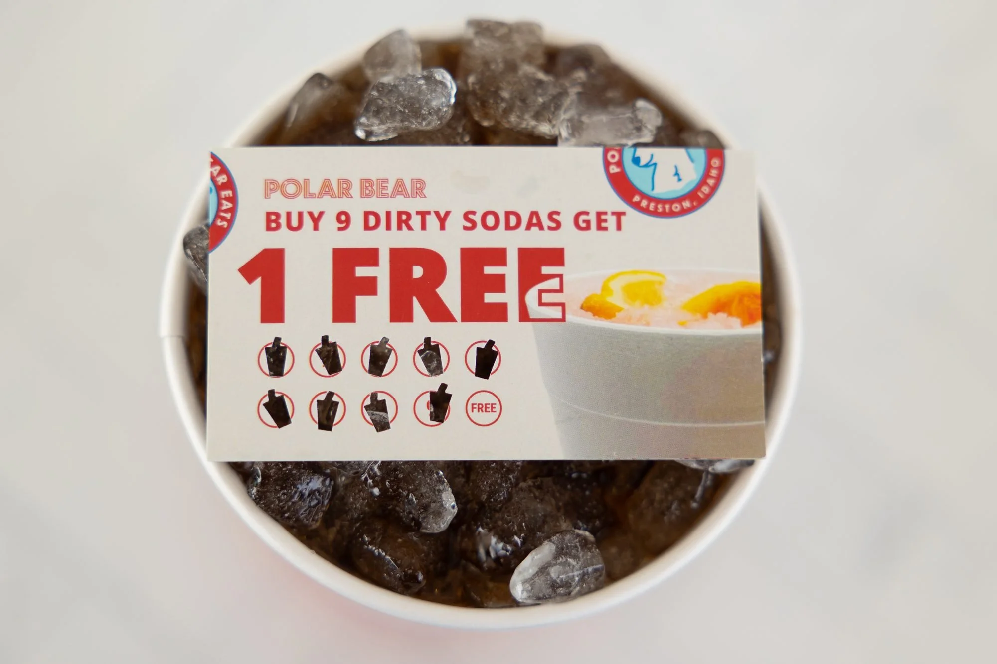 A cup of iced soda with a Polar Bear punch card tucked in the top