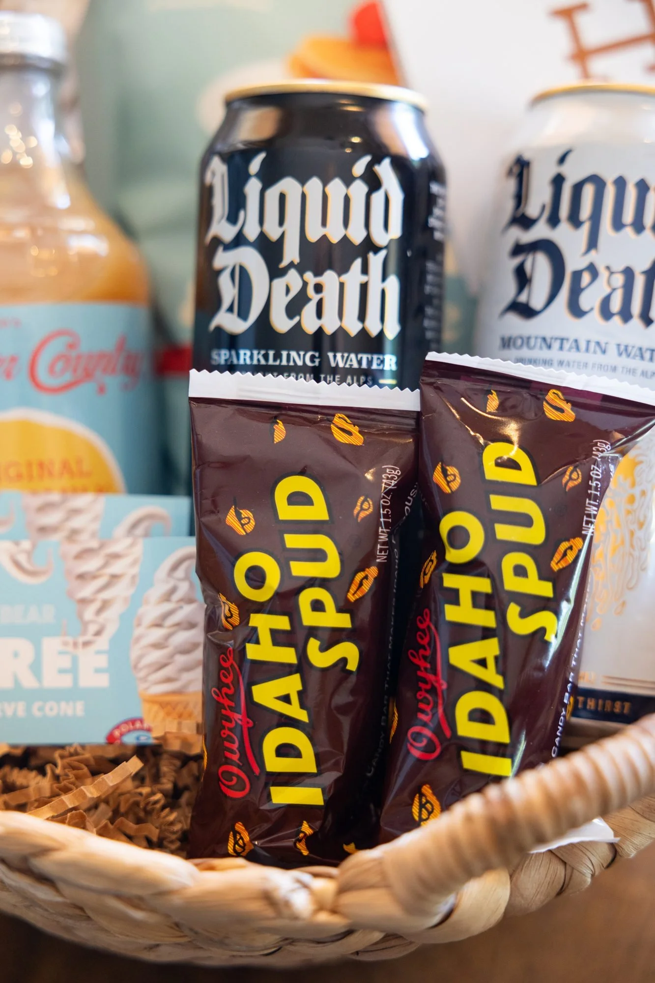 Close view of canned sparkling water and wrapped candy bars tucked into a woven basket