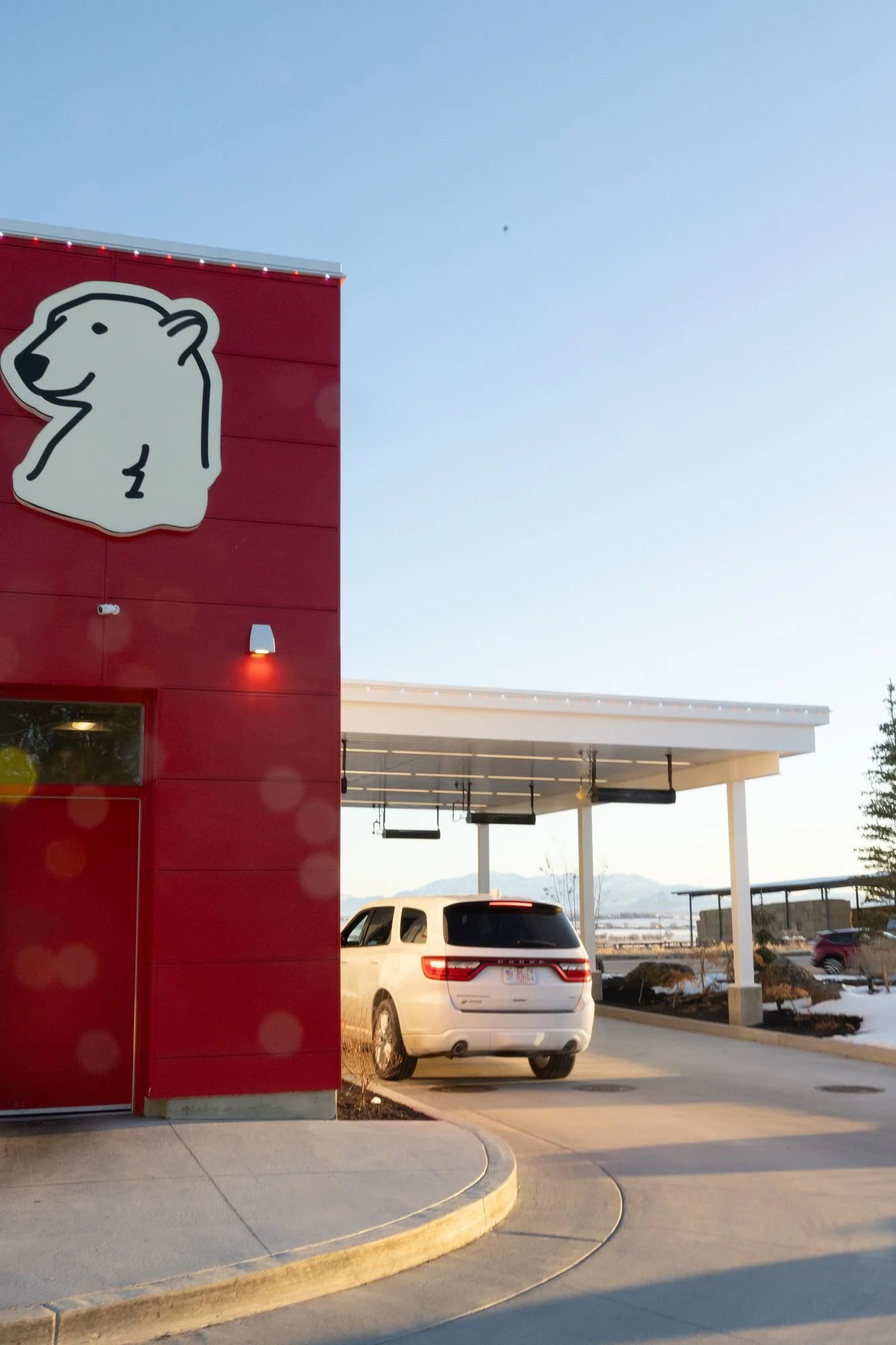 A red Polar Bear building with a polar bear logo beside a drive-through canopy and a white SUV