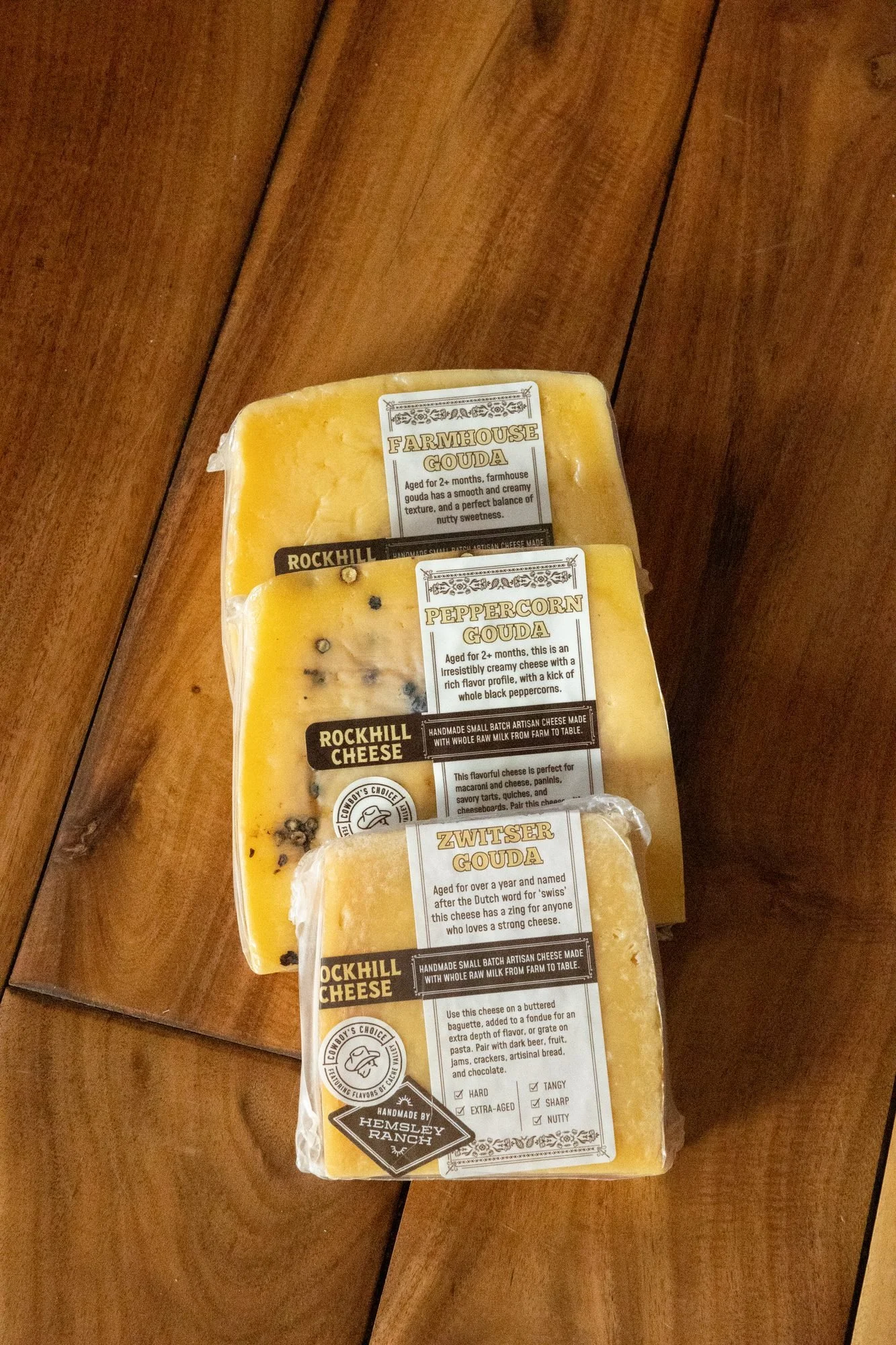 Three wrapped wedges of Rockhill Cheese stacked on a wooden surface