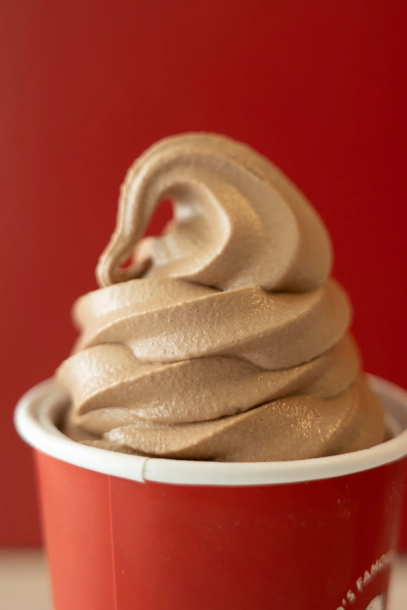 Close view of chocolate soft serve swirl in a red cup