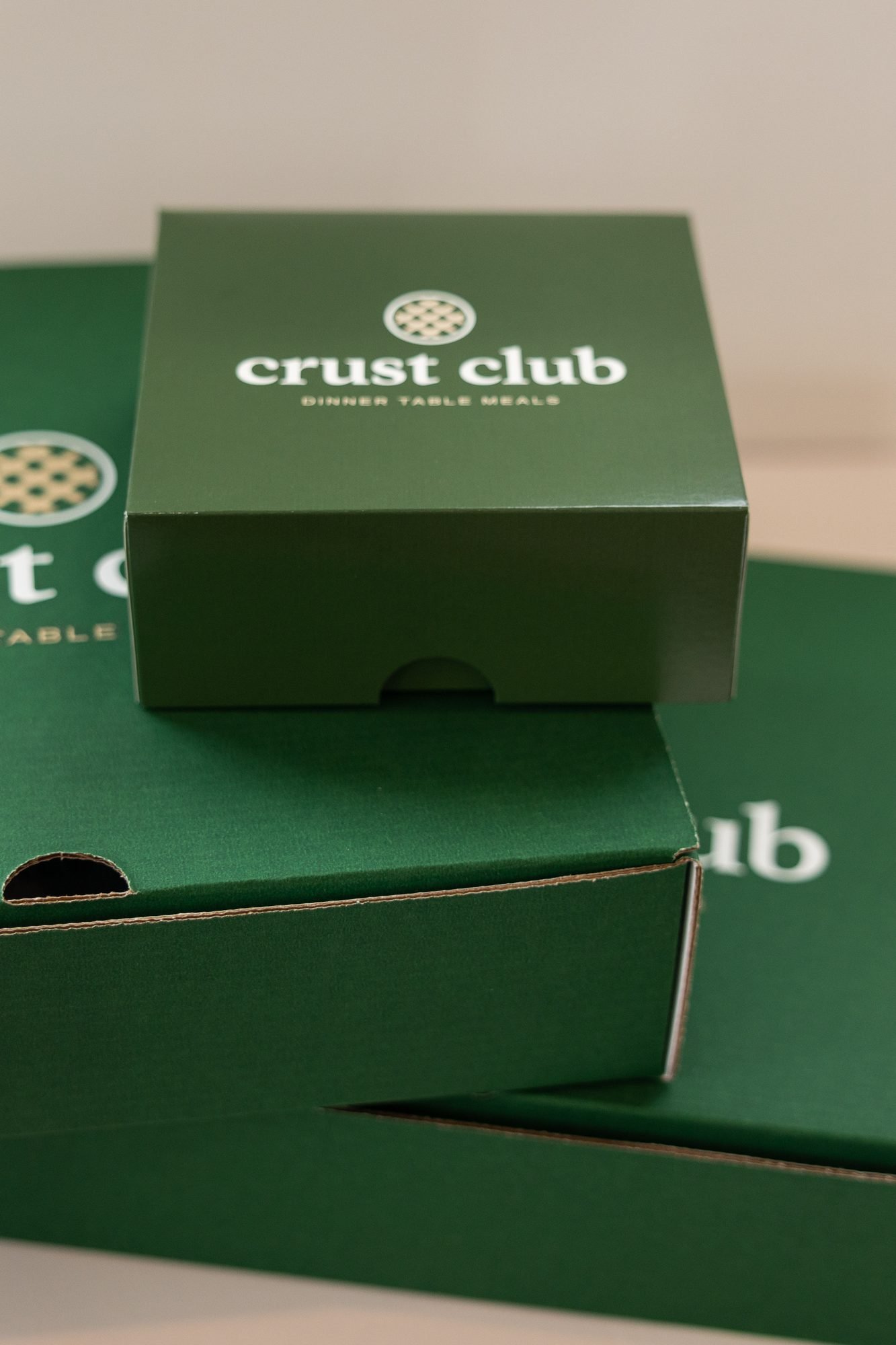 A stack of green Crust Club boxes on a white surface