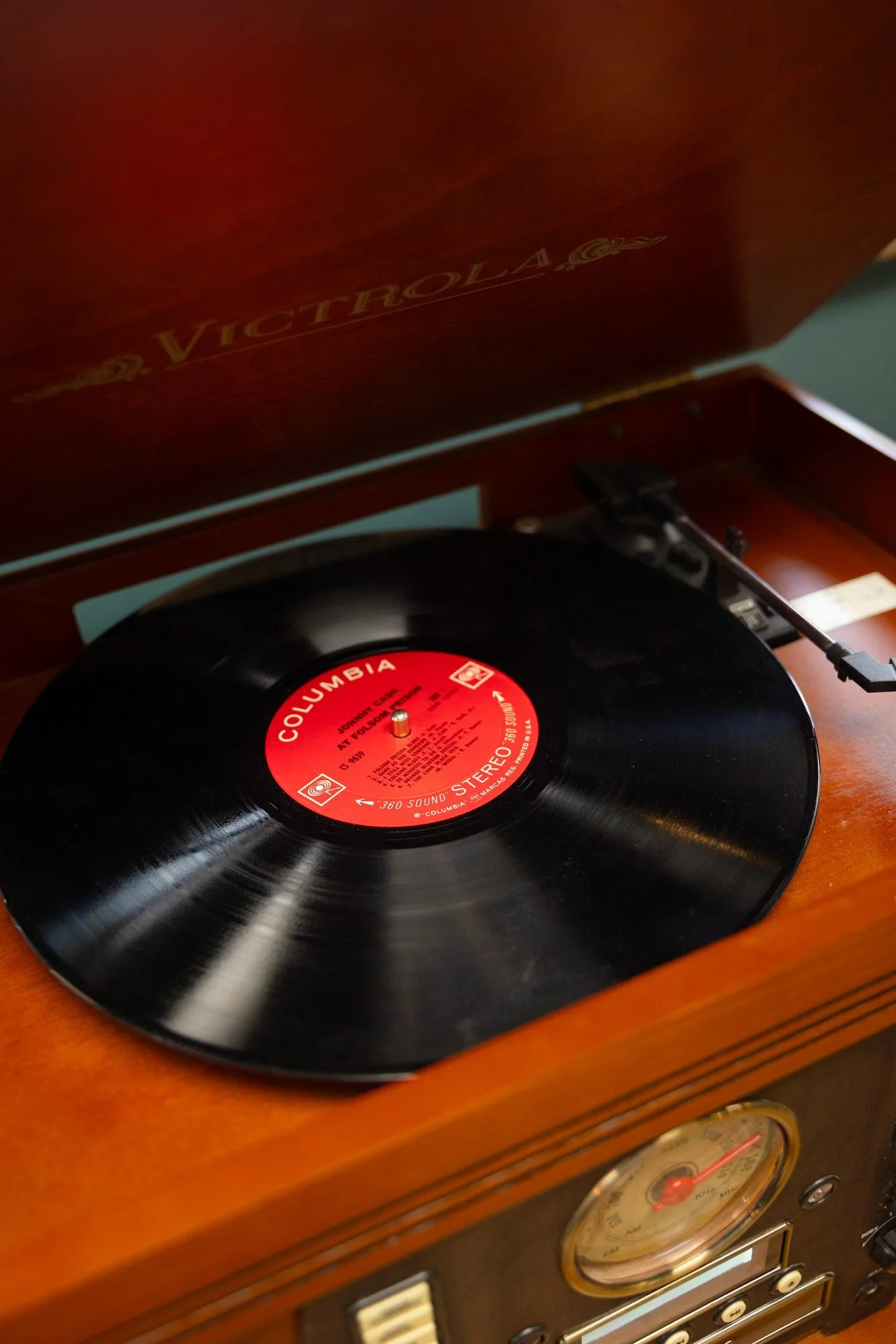 A vinyl record on the turntable of a wooden Victrola record player