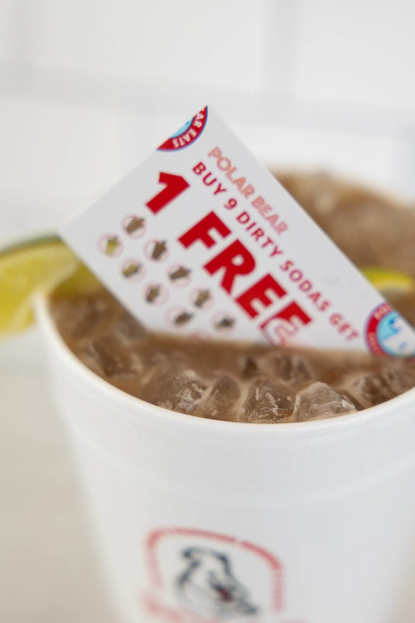 A Polar Bear punch card tucked into a cup of iced soda with a lime wedge
