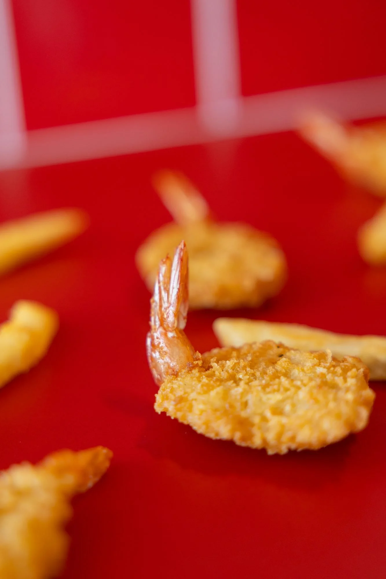 Fried shrimp and fries scattered across a red surface