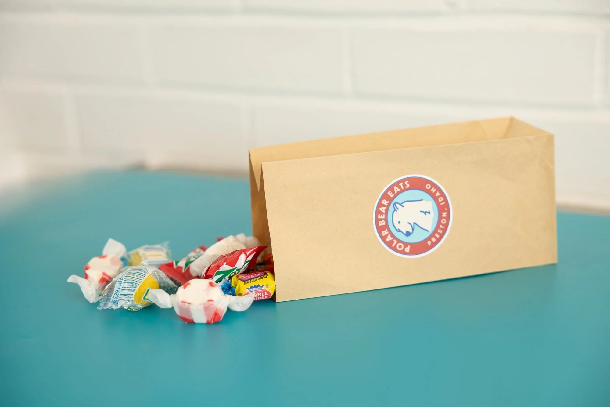 A Polar Bear paper bag on its side with wrapped candies spilling onto a teal surface