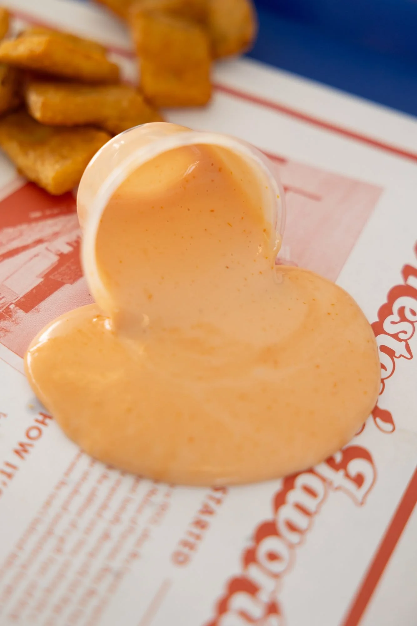 A tub of pink dipping sauce tipped over on a printed Polar Bear tray liner