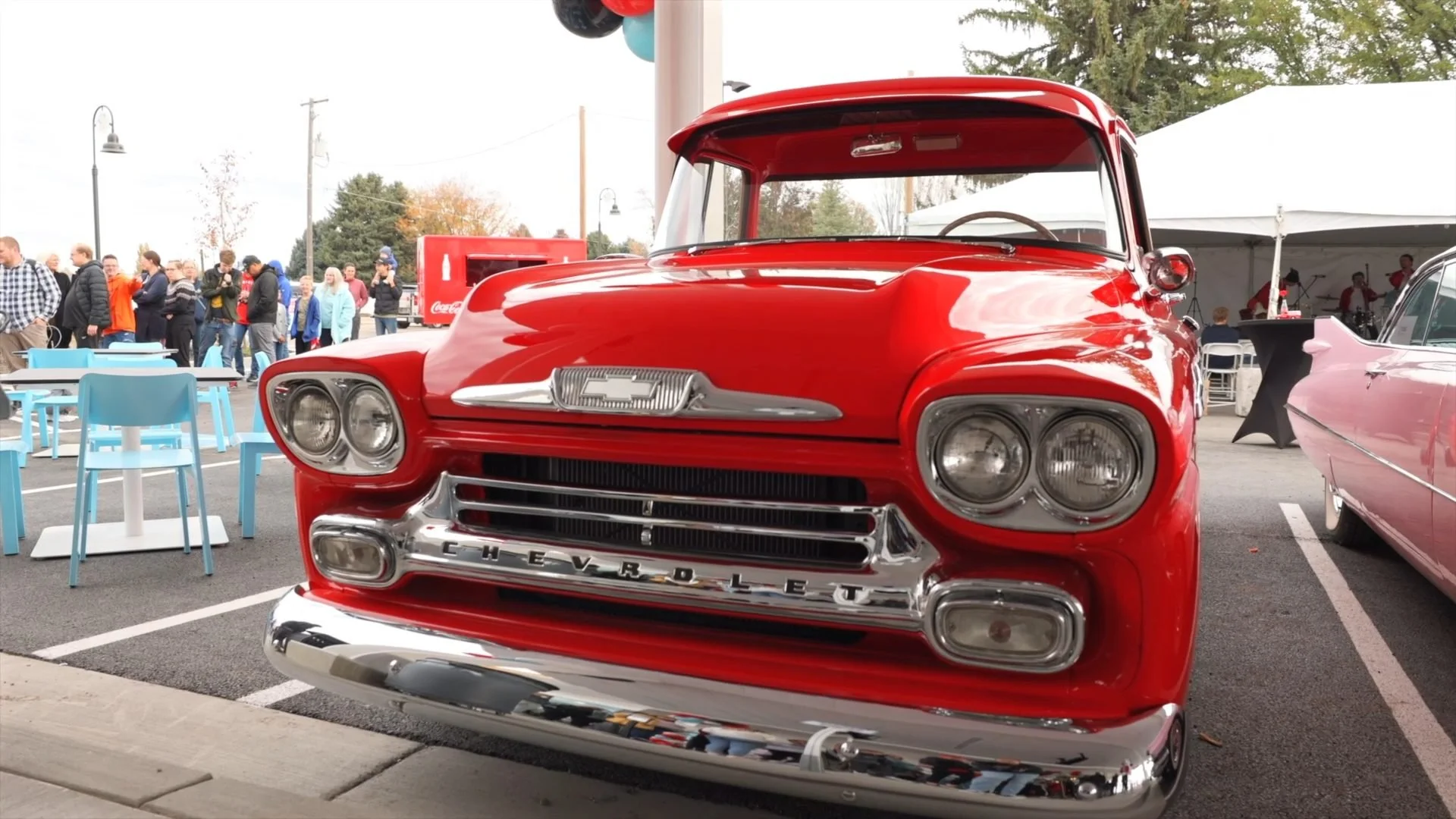 A classic red pickup truck parked at a busy outdoor event