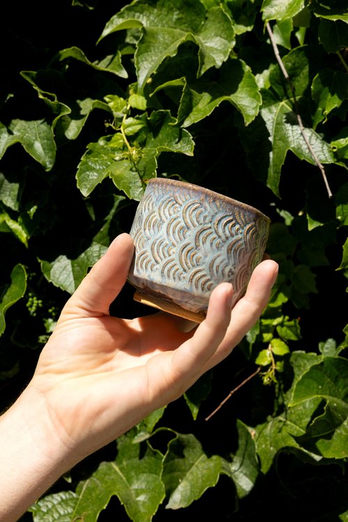 Textured stoneware cup by Adam Corbridge Pottery held against ivy