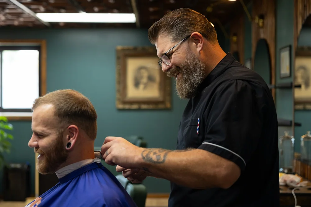 Barber laughing with a client at Cache Cuts barbershop in Cache Valley, Utah