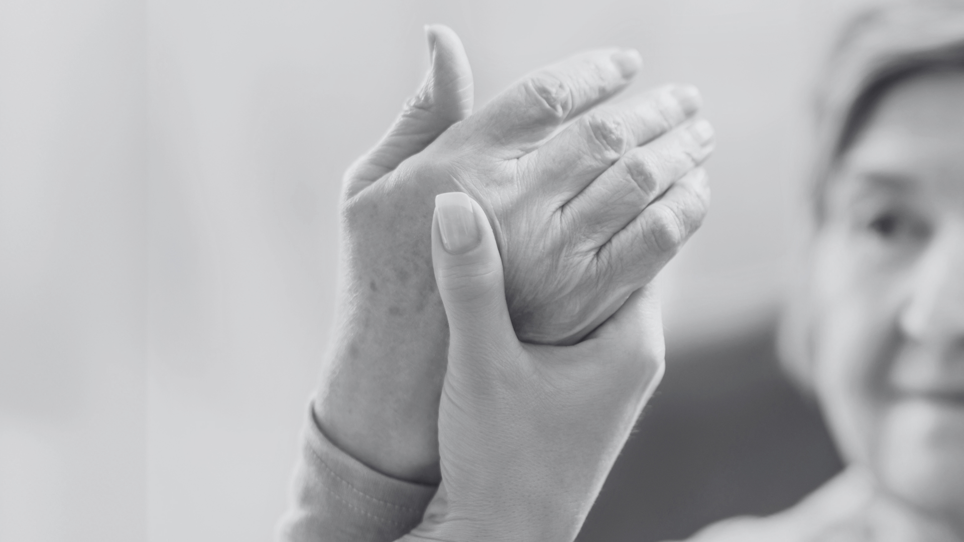 A physical therapist gently working on a senior patient's hand,  helping relieve tightness and pain.