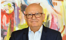 Bald man with glasses a dark suit and stripped button up shirt
