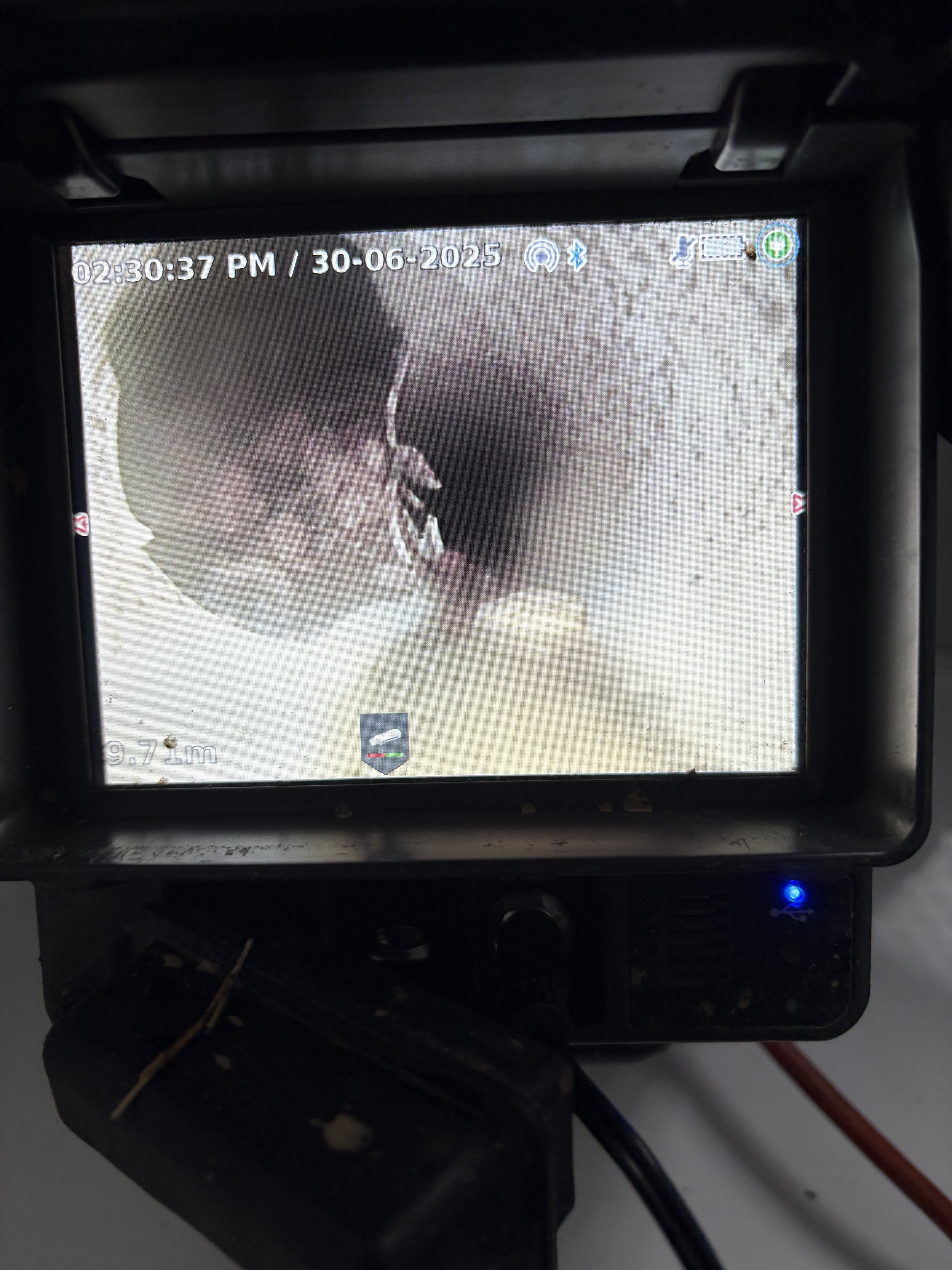 Close up of a CCTV drain inspection camera showing a broken pipe with concrete blocking it.