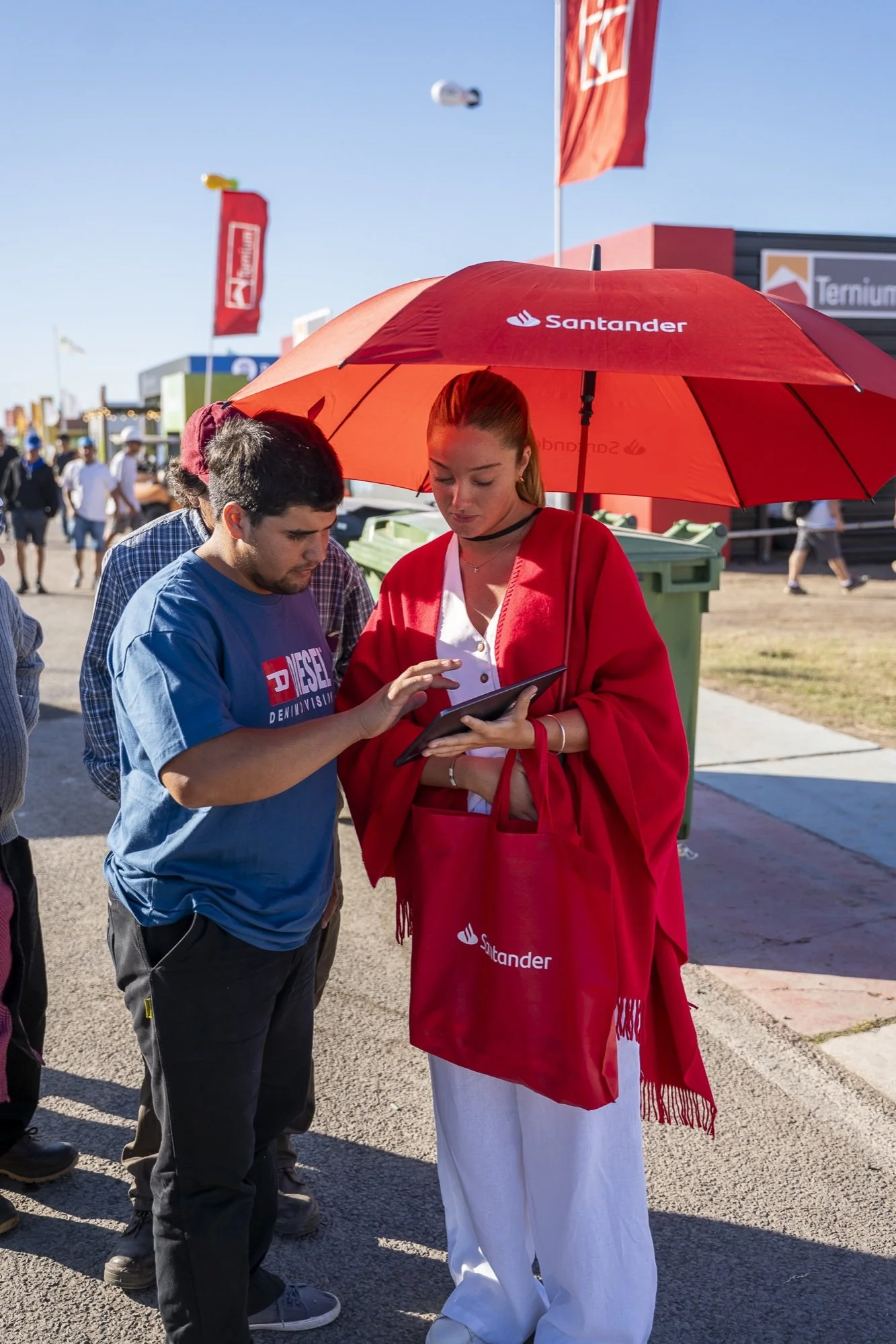 Promotora de Santander con paraguas rojo atendiendo a un visitante en Expoagro