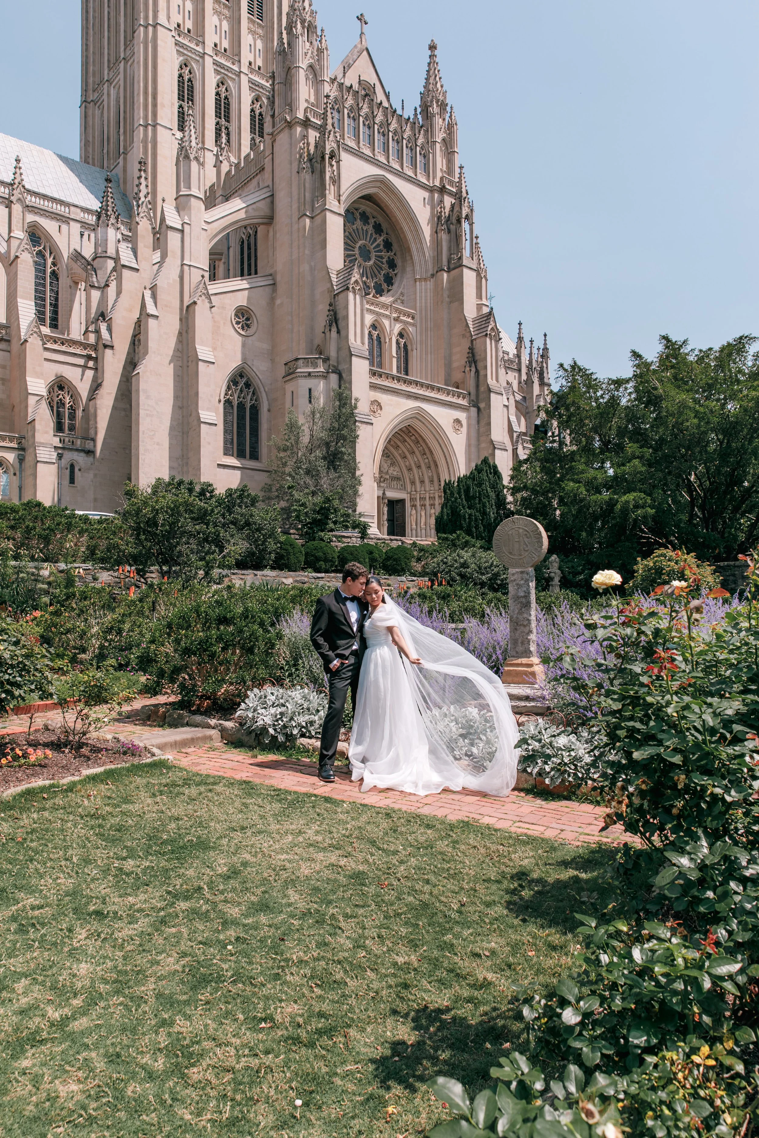 A bride and groom standing in front of the National Cathedral during their elopement in the Bishop's Garden in Washington DC.