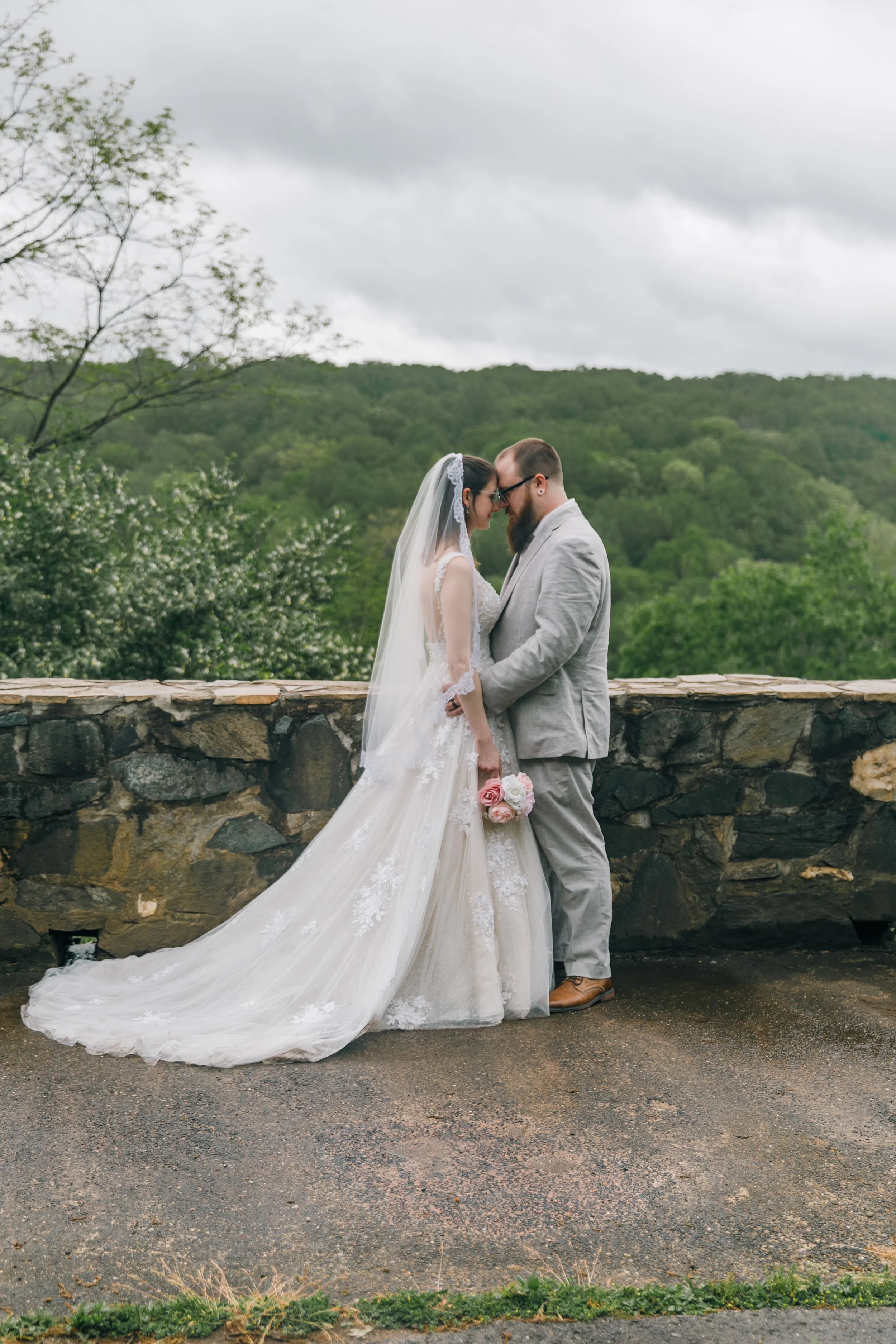 A couple sharing an intimate moment on their elopement day in front of a cloudy overlook in Maryland photographed by a Maryland Elopement Photographer