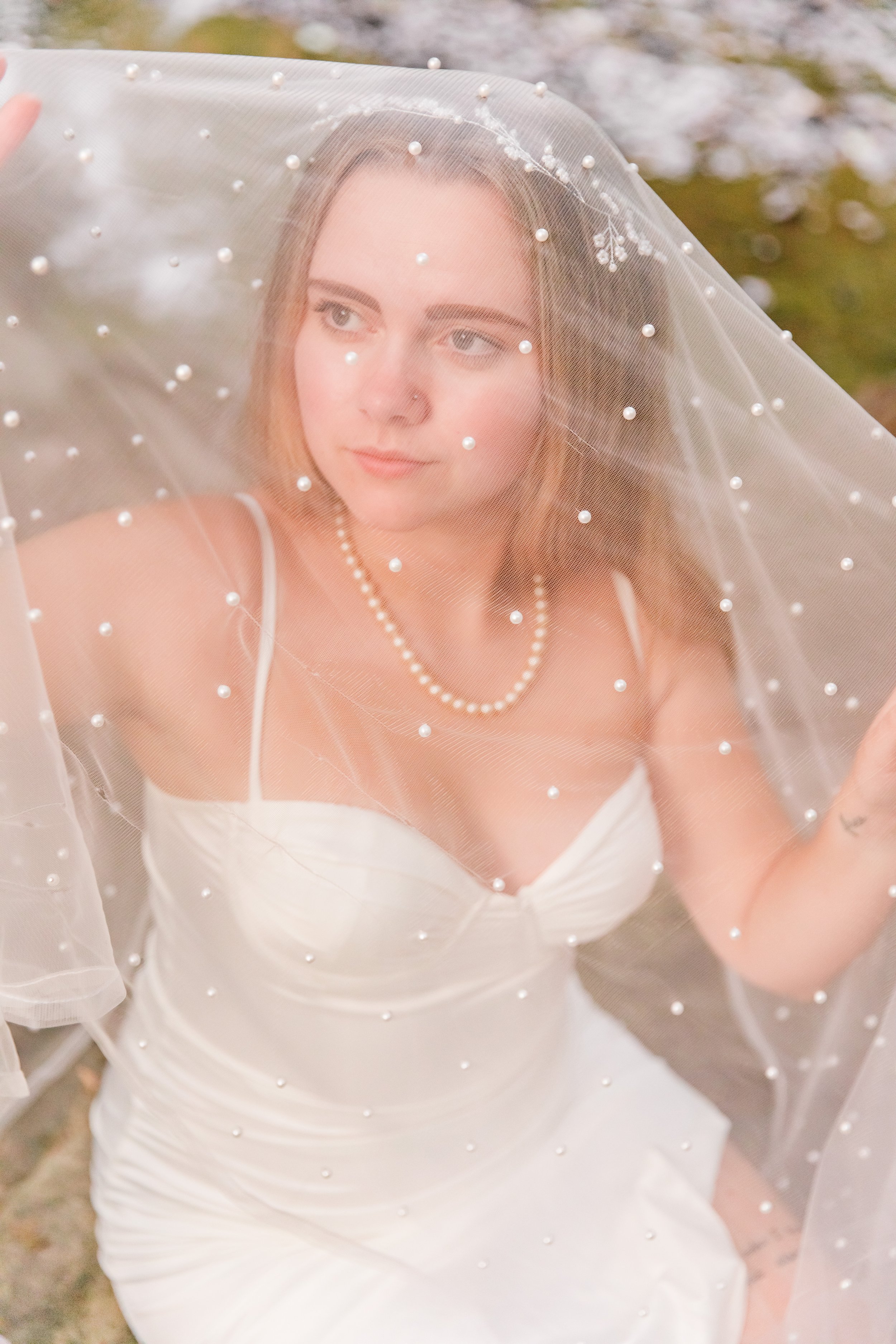 A bride looking regal under her pearl-studded veil at her elopement at Rocks Creek Park in Washington DC.