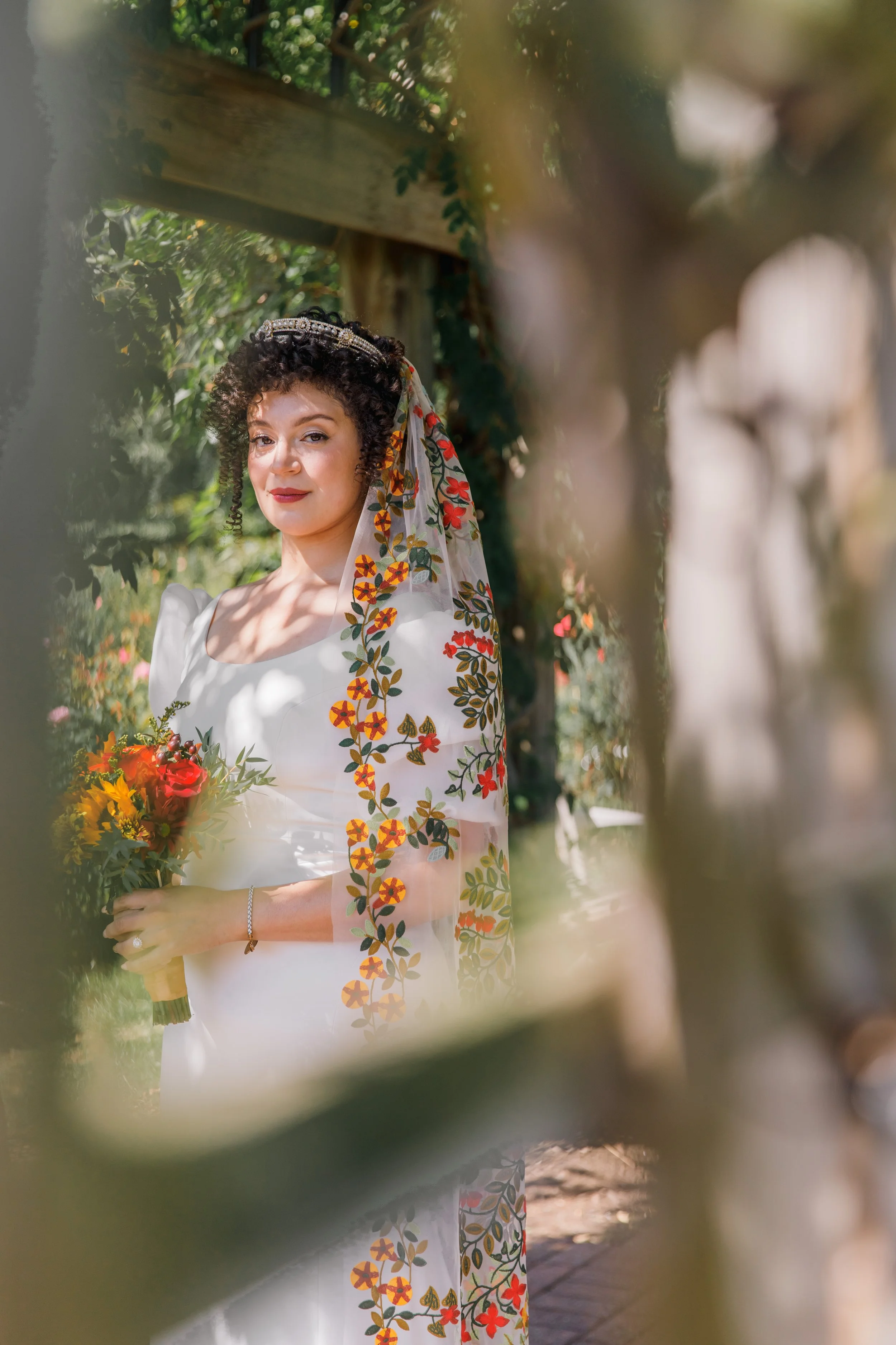 A bride peering through the trellis at Bon Air Rose Garden during her bridal portraits before her elopement in Virginia.