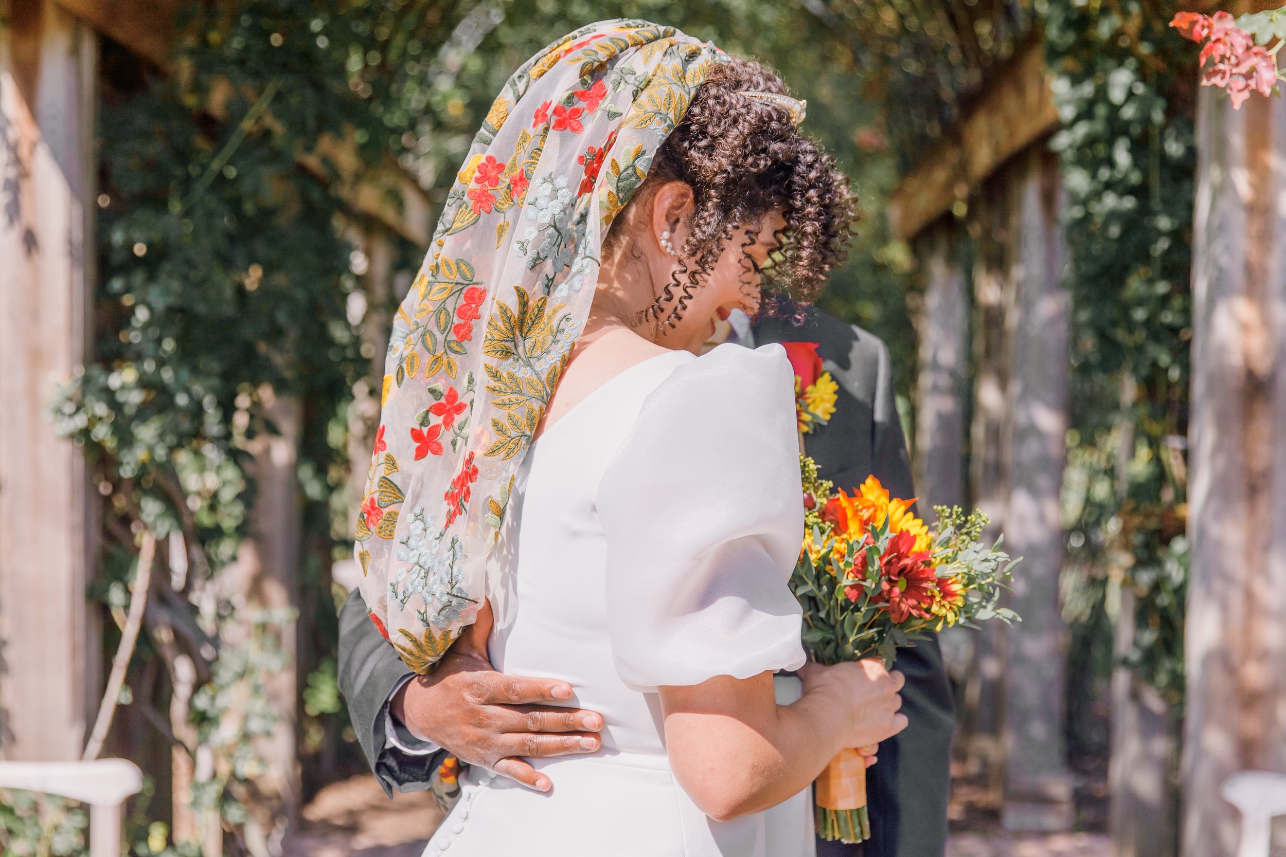 A bride is smiling and being led by her groom before their elopement at the Bon Air Rose Garden in Arlington Virginia.