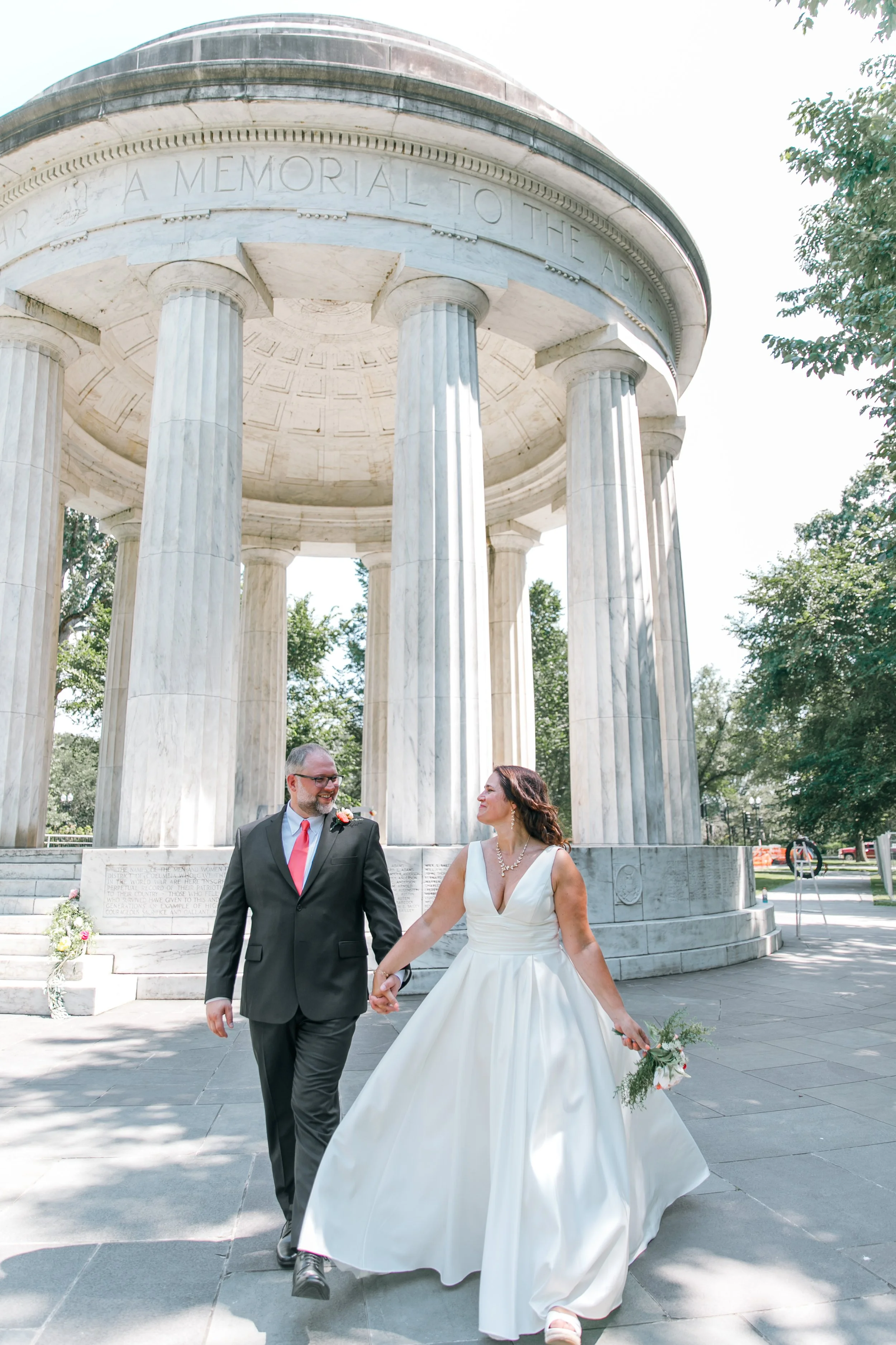 A bride and groom walking away smiling at the DC War Memorial at their elopement in Washington DC.