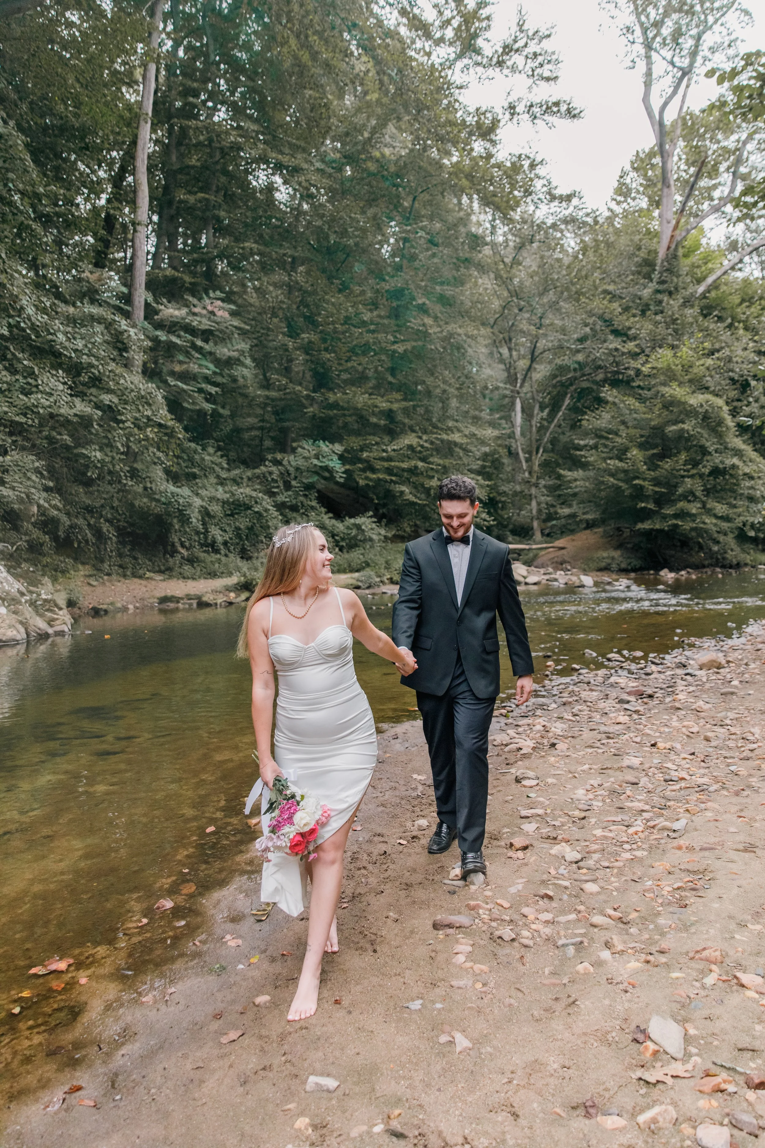 A bride and groom playfully walking along the creek before their elopement at Rocks Creek Park in Washington DC.