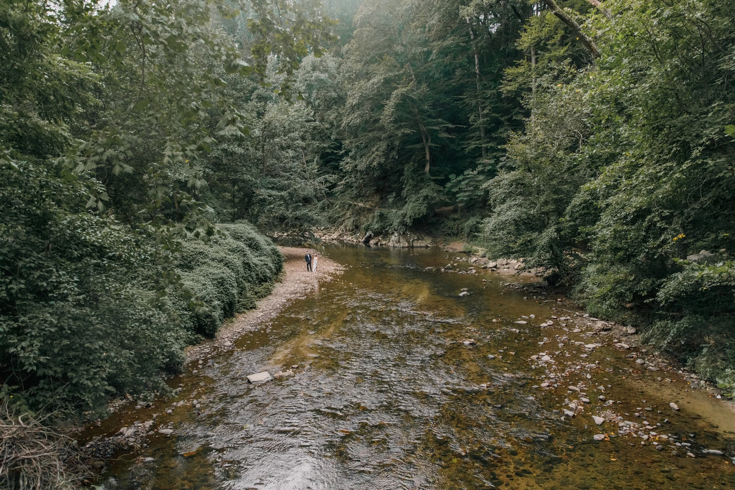 A bride and groom standing by the water during their elopement at Rocks Creek Park in Washington DC.