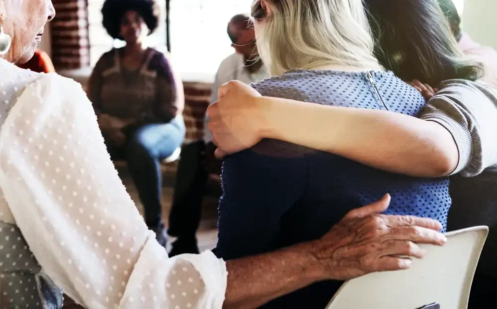 people sitting in a circle. some with arms around each other