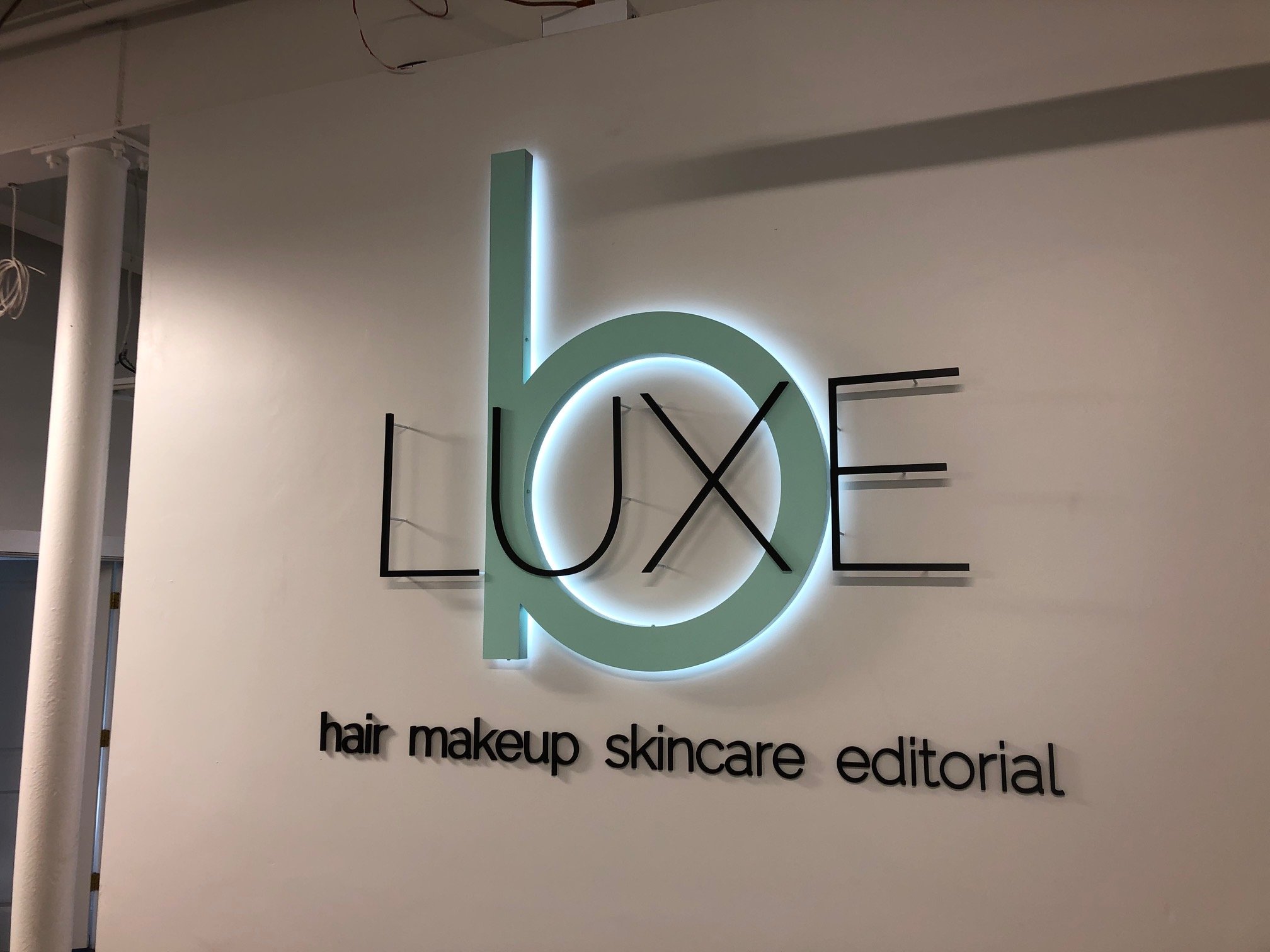 Sign with the word 'LOVE' in large illuminated letters, with the words 'hair makeup skincare editorial' below.
