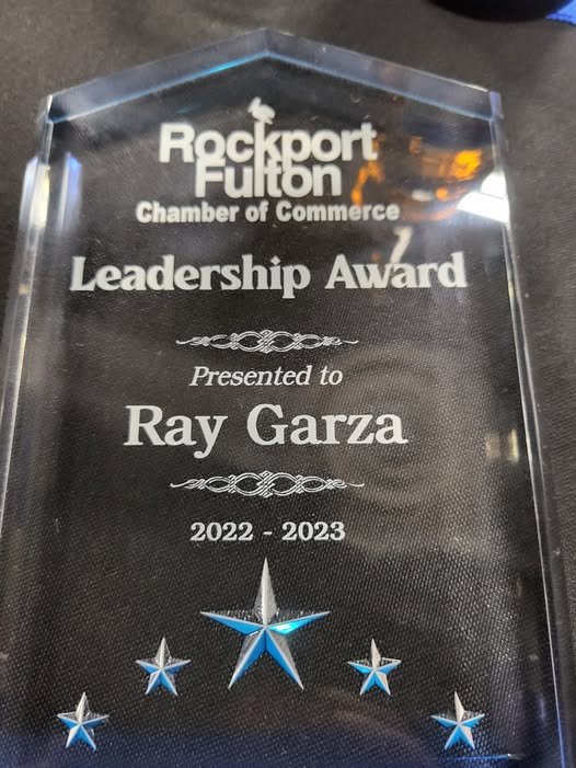 Glass leadership award plaque from Rockport Fulton Chamber of Commerce awarded to Ray Garza for 2022-2023, featuring star designs at the bottom.