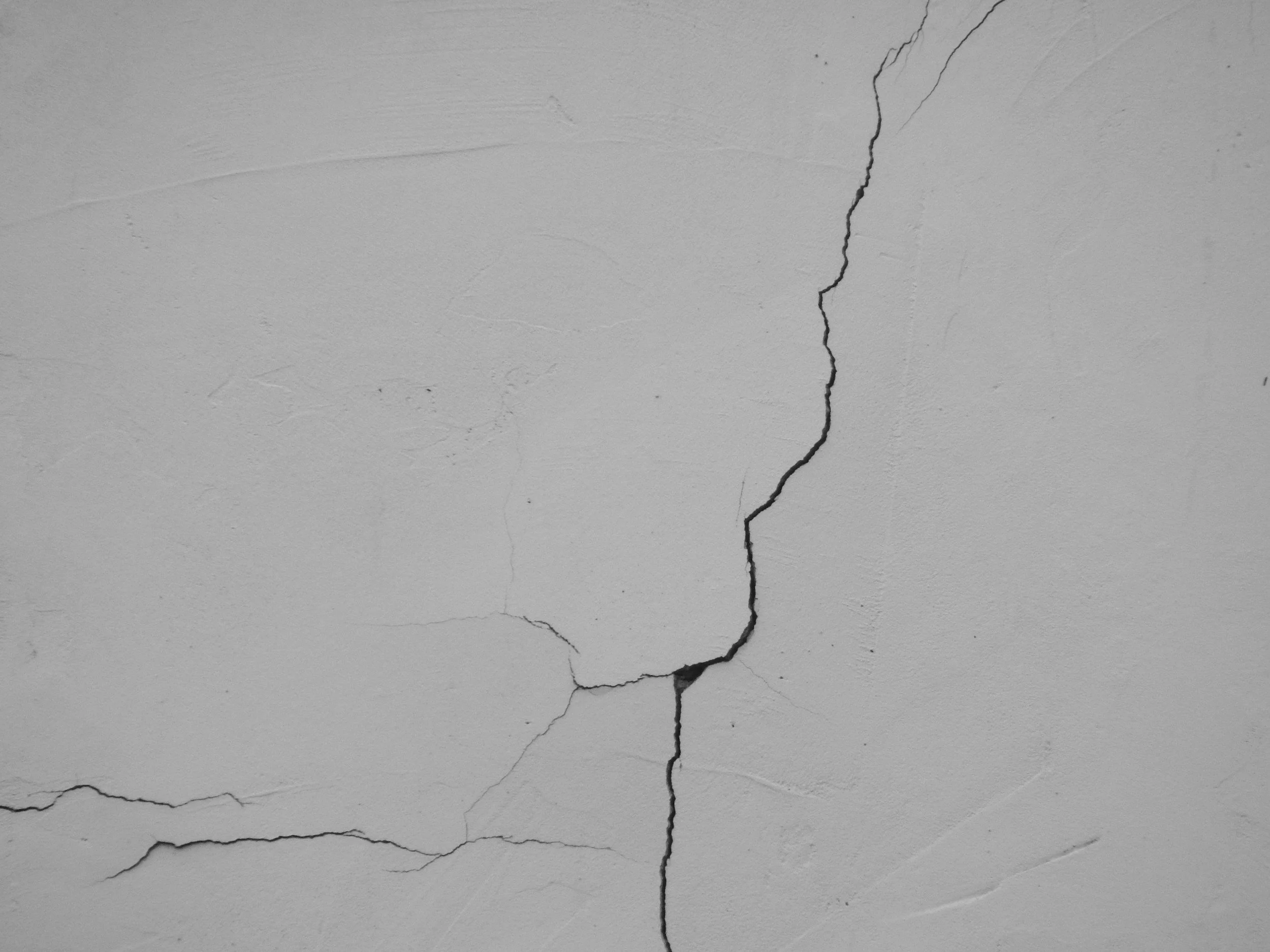 Close-up image of a white wall with a large, central crack in the plaster.