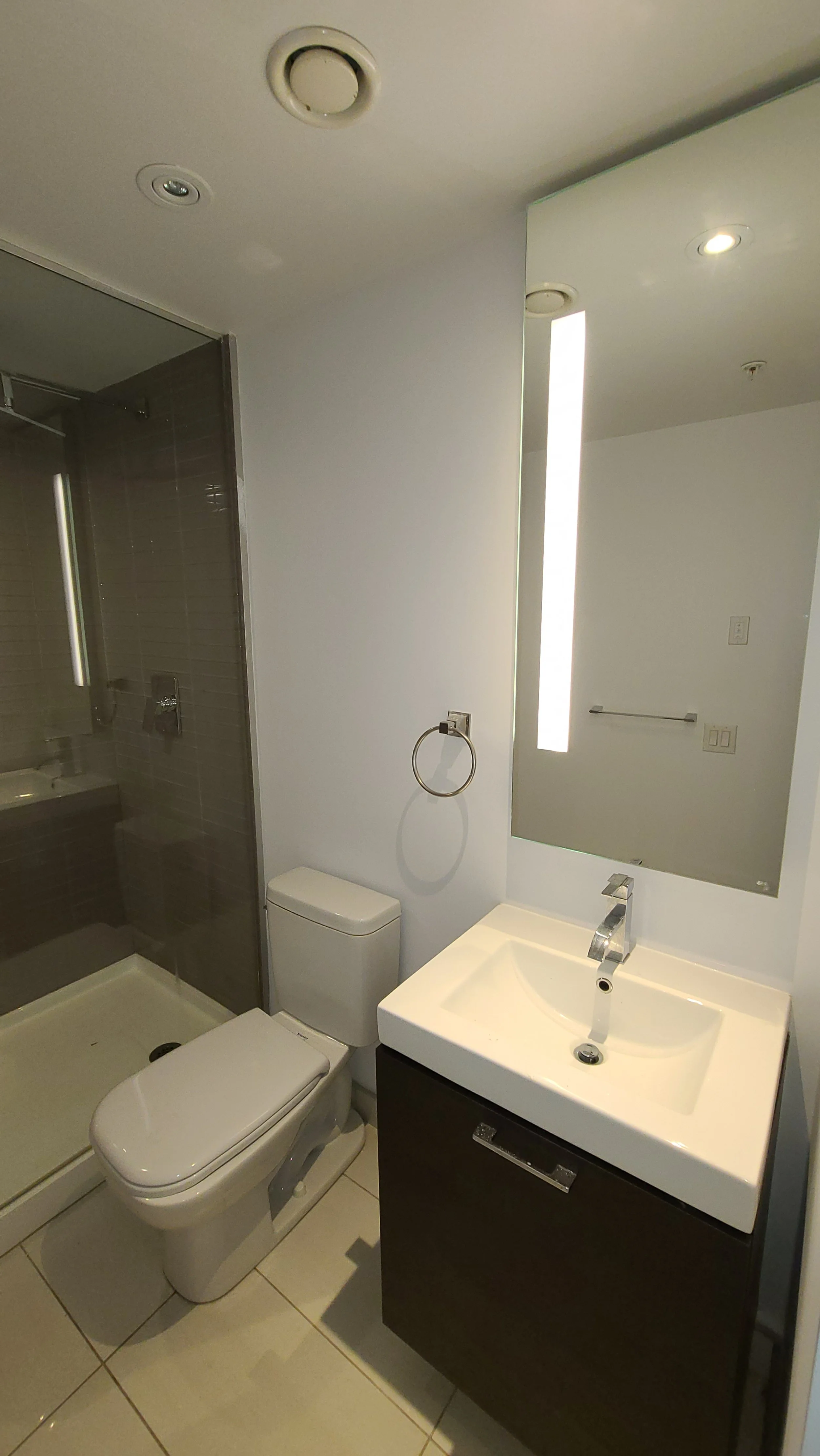 Modern bathroom with a shower stall, toilet, and a small sink with a mirror above.