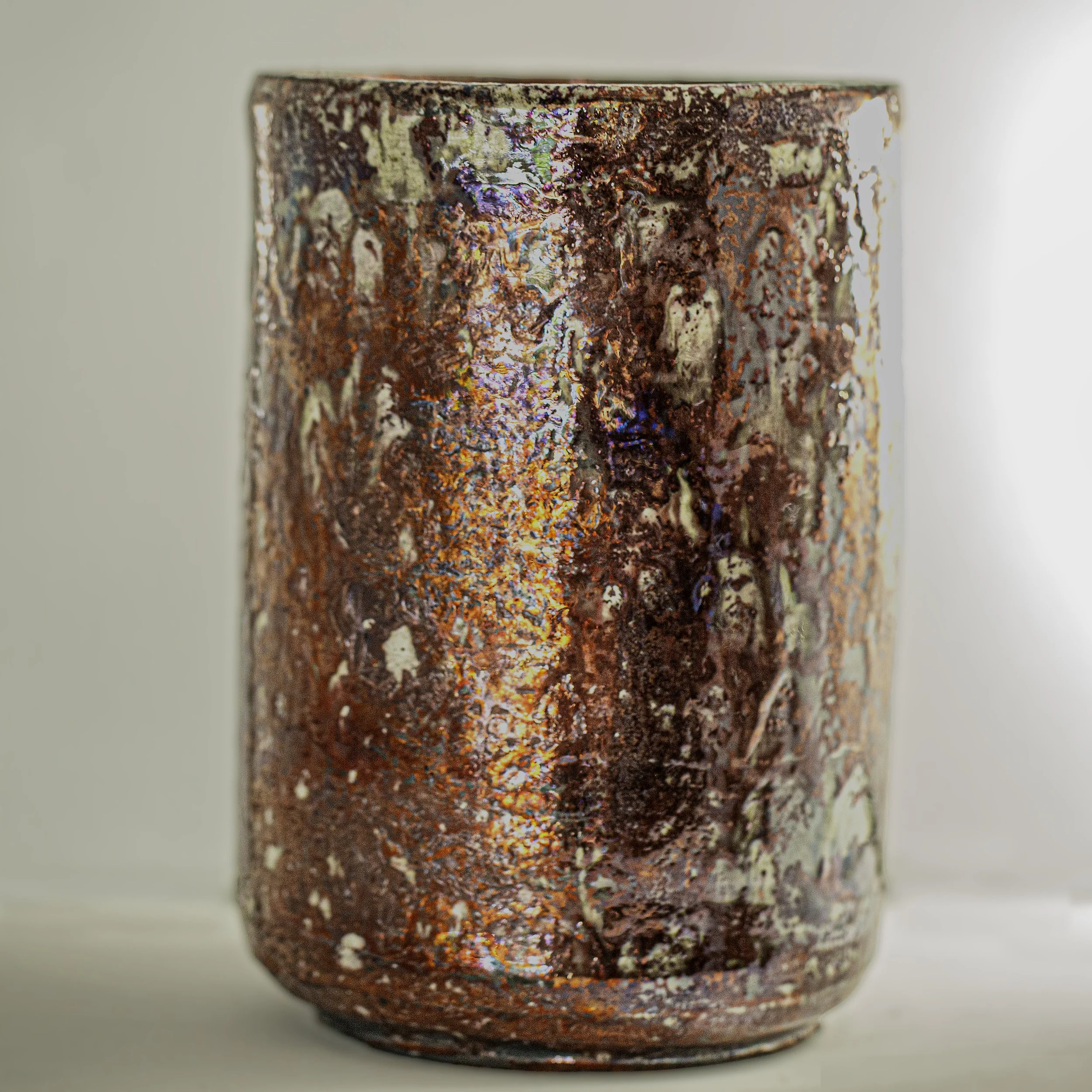 Close-up of a ceramic vase with a textured, multicolored glaze featuring shades of red, orange, and cream.