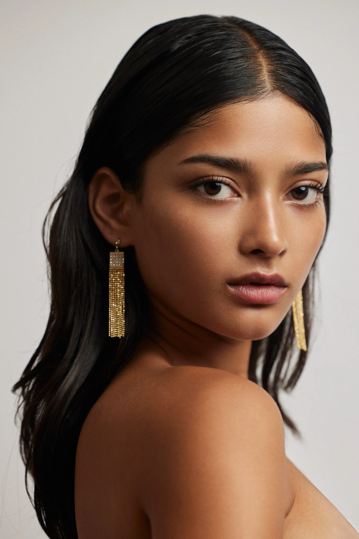 Studio headshot of model with bold gold earrings for beauty brand campaign