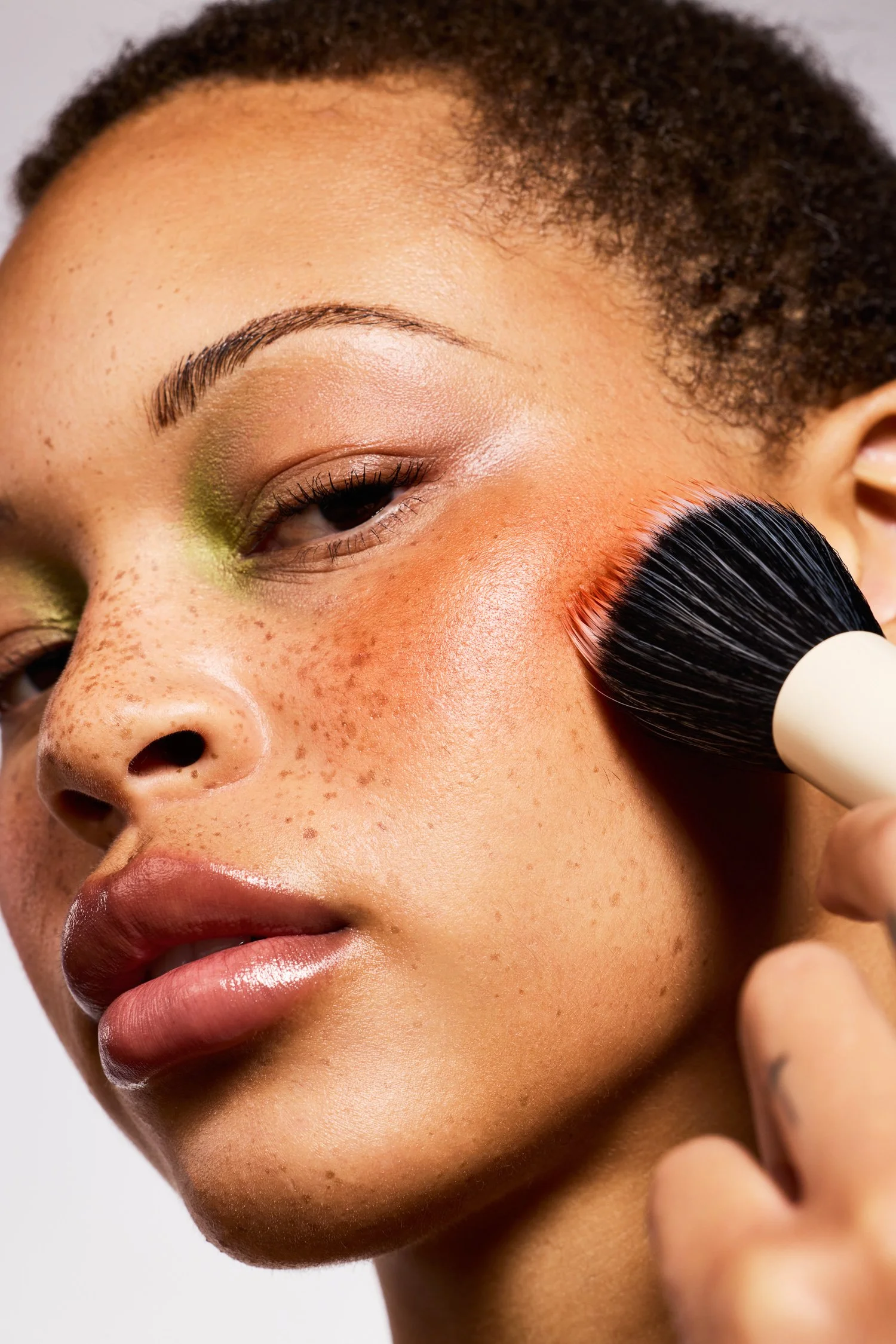 Makeup application with blush brush and vibrant colors for editorial beauty shoot in LA