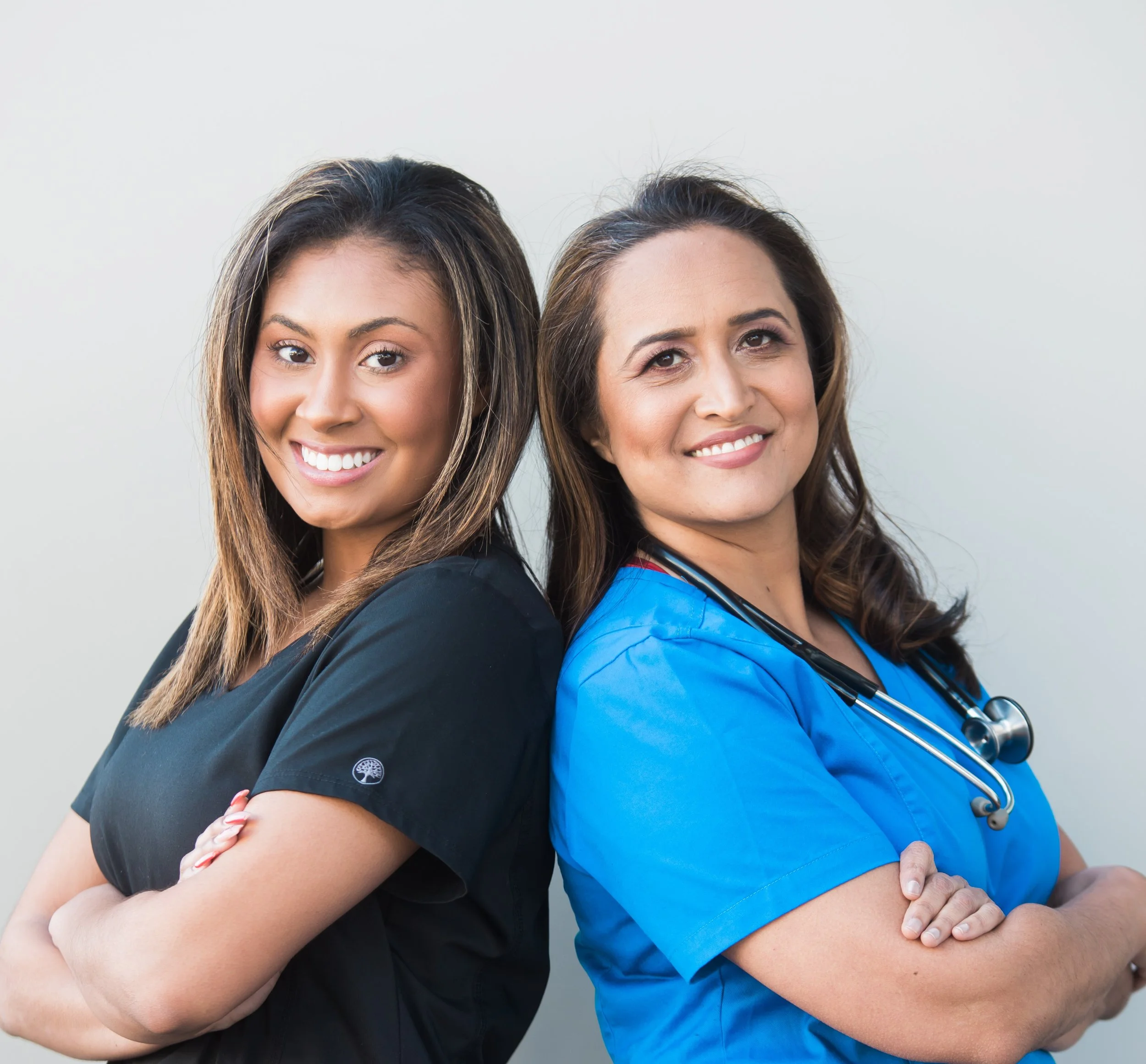 2 nurses smiling facing back to back