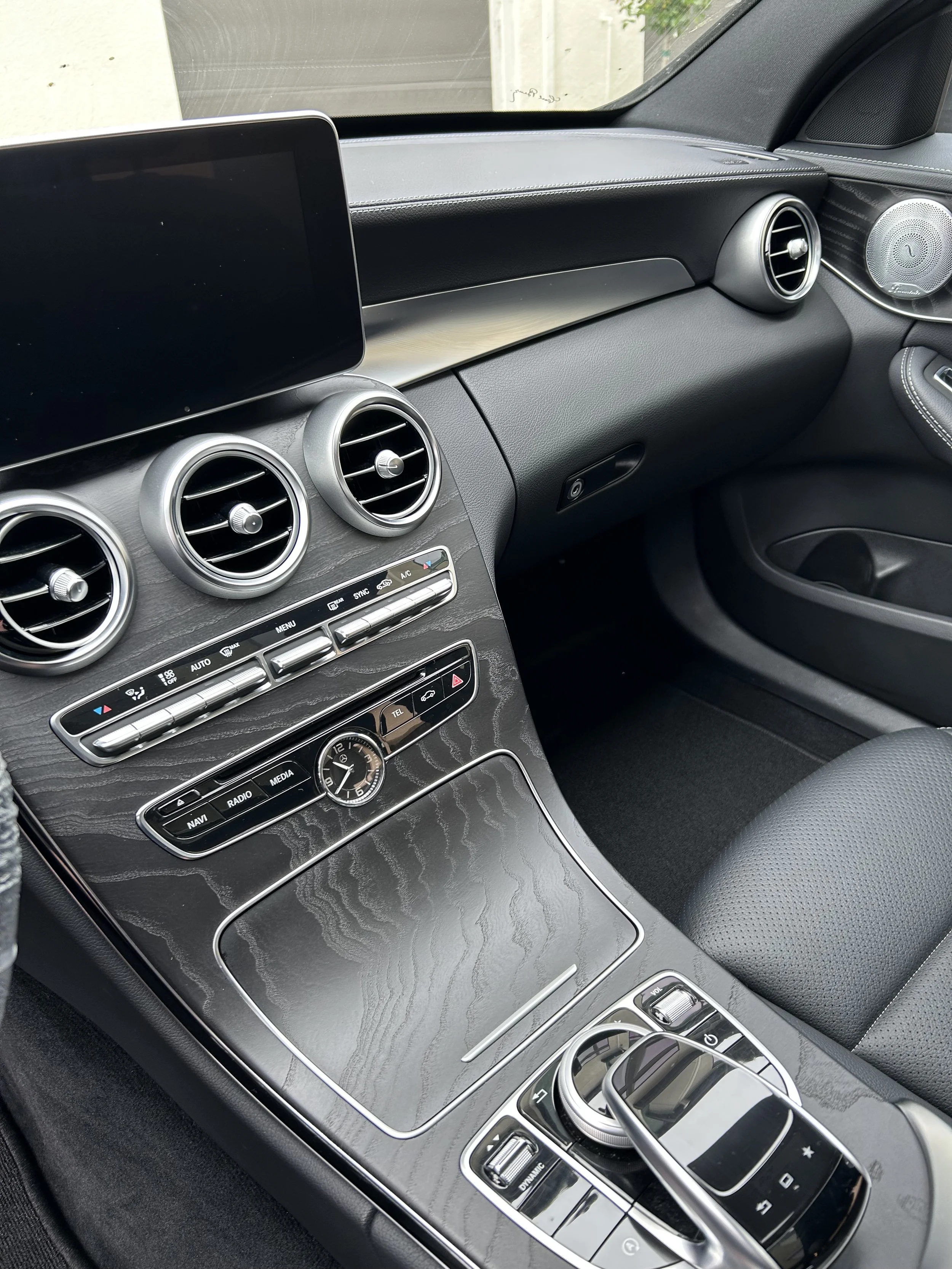 Interior of a modern car showing dashboard, air vents, control panel, and gear shift.