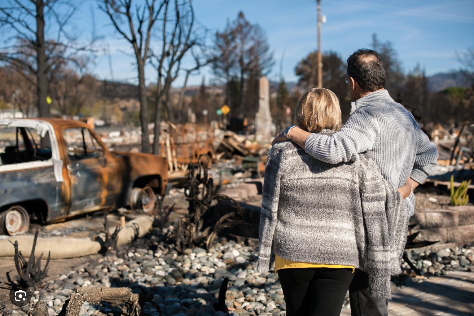 Couple looks on at the ruins of their home after devastating fire