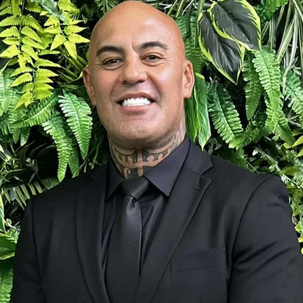 Portrait shot of Phil Turner, Owner & Managing Director of Simplicity Funeral Home in Hamilton, smiling in front of a greenery backdrop.