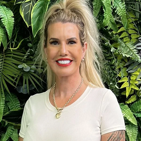 Portrait shot of Carla Turner, Owner & Managing Director at Simplicity Funeral Home in Hamilton, smiling in front of a greenery backdrop.