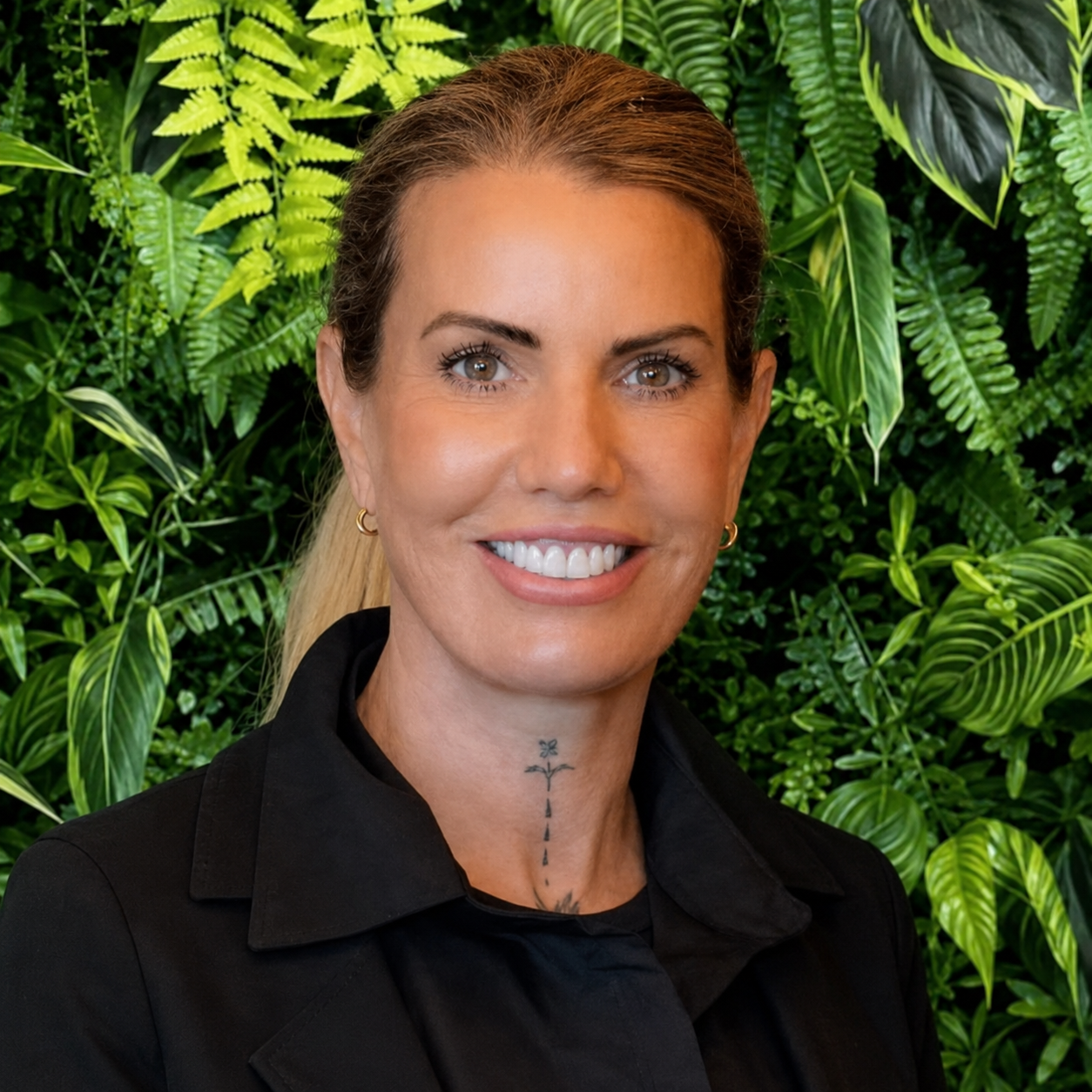 Portrait shot of Carla Turner, Owner & Managing Director of Simplicity Funeral Home in Hamilton, smiling in front of a greenery backdrop.