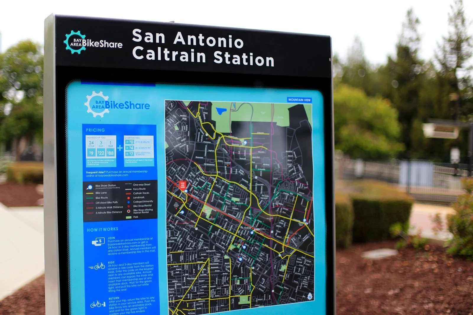 Information sign for San Antonio Caltrain Station with a map of bike routes, pricing, and instructions for bike share usage.