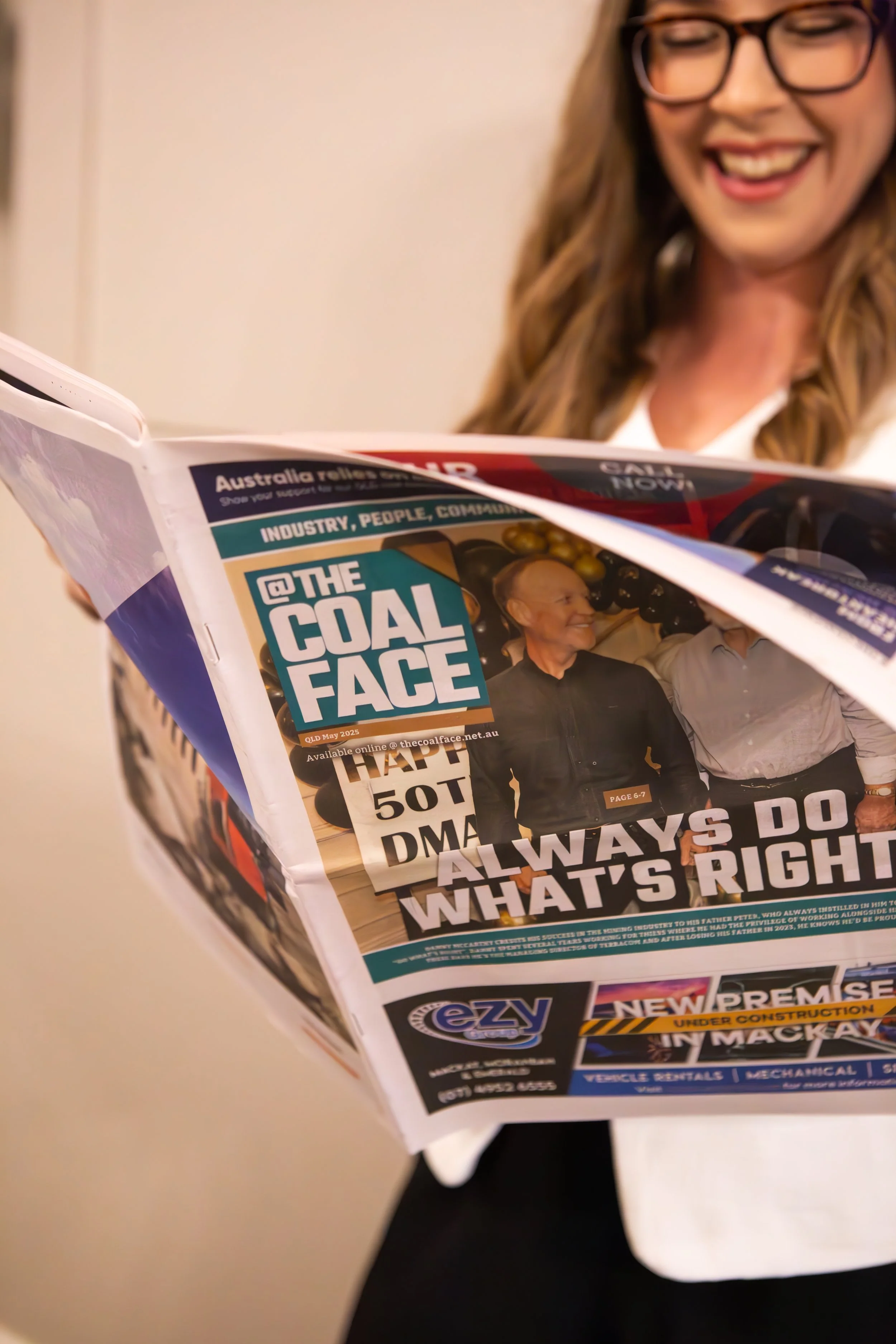 woman smiling while reading at the coalface newspaper